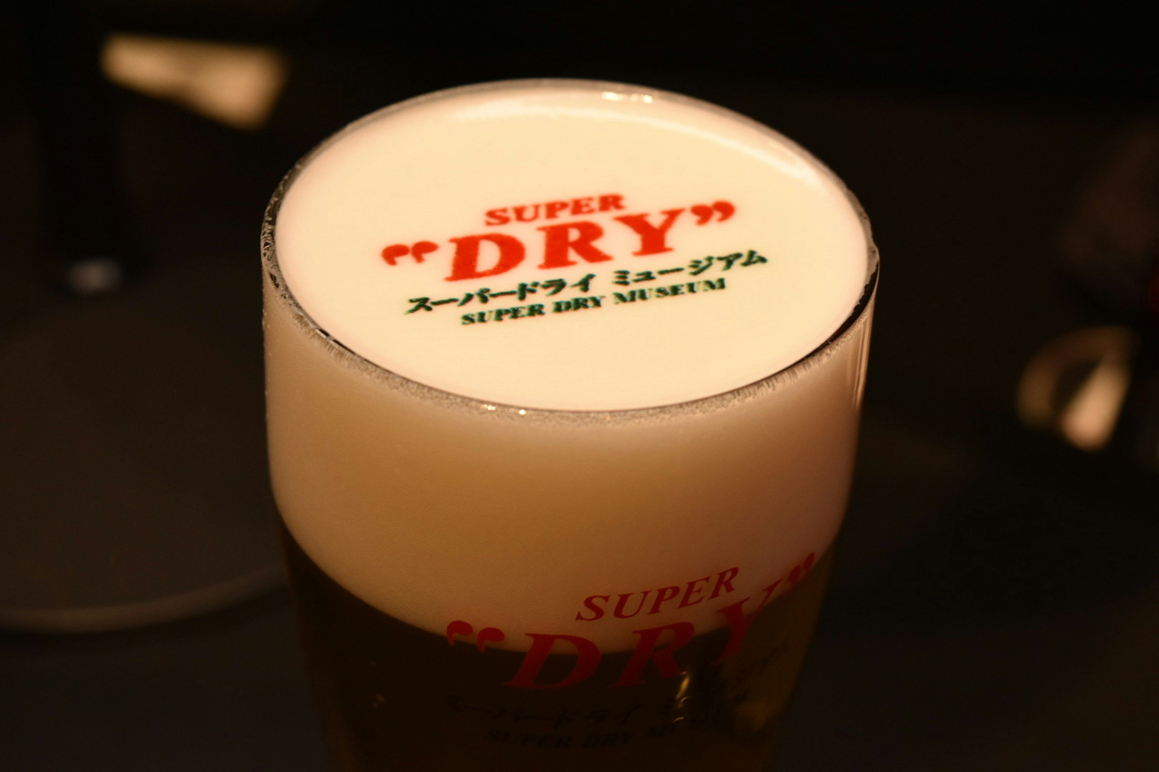 ビールのグラスに乗った泡の上に「SUPER DRY」と書かれたデザイン