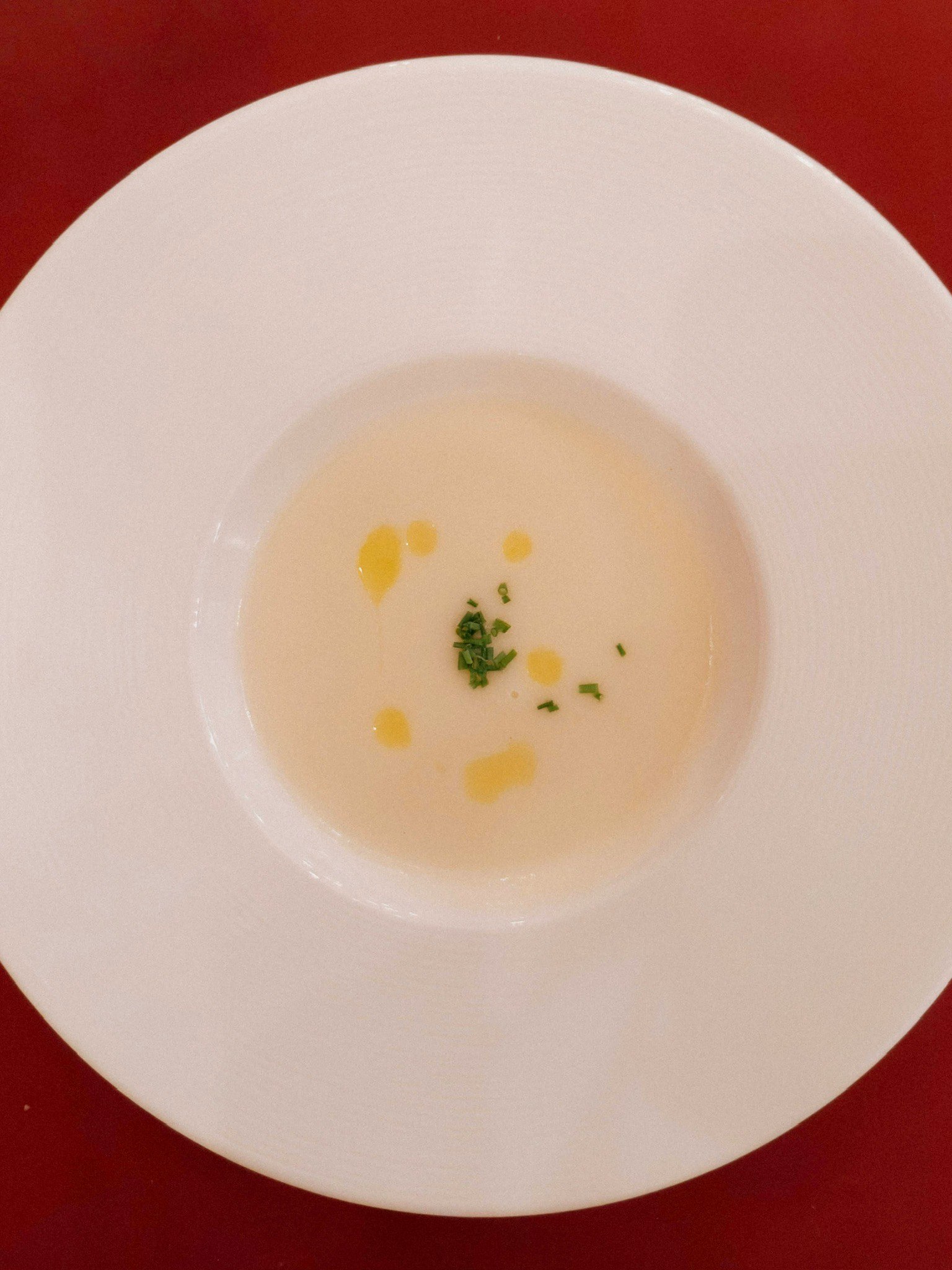 Soupe blanche dans une assiette creuse avec garniture d'huile d'olive et d'herbes