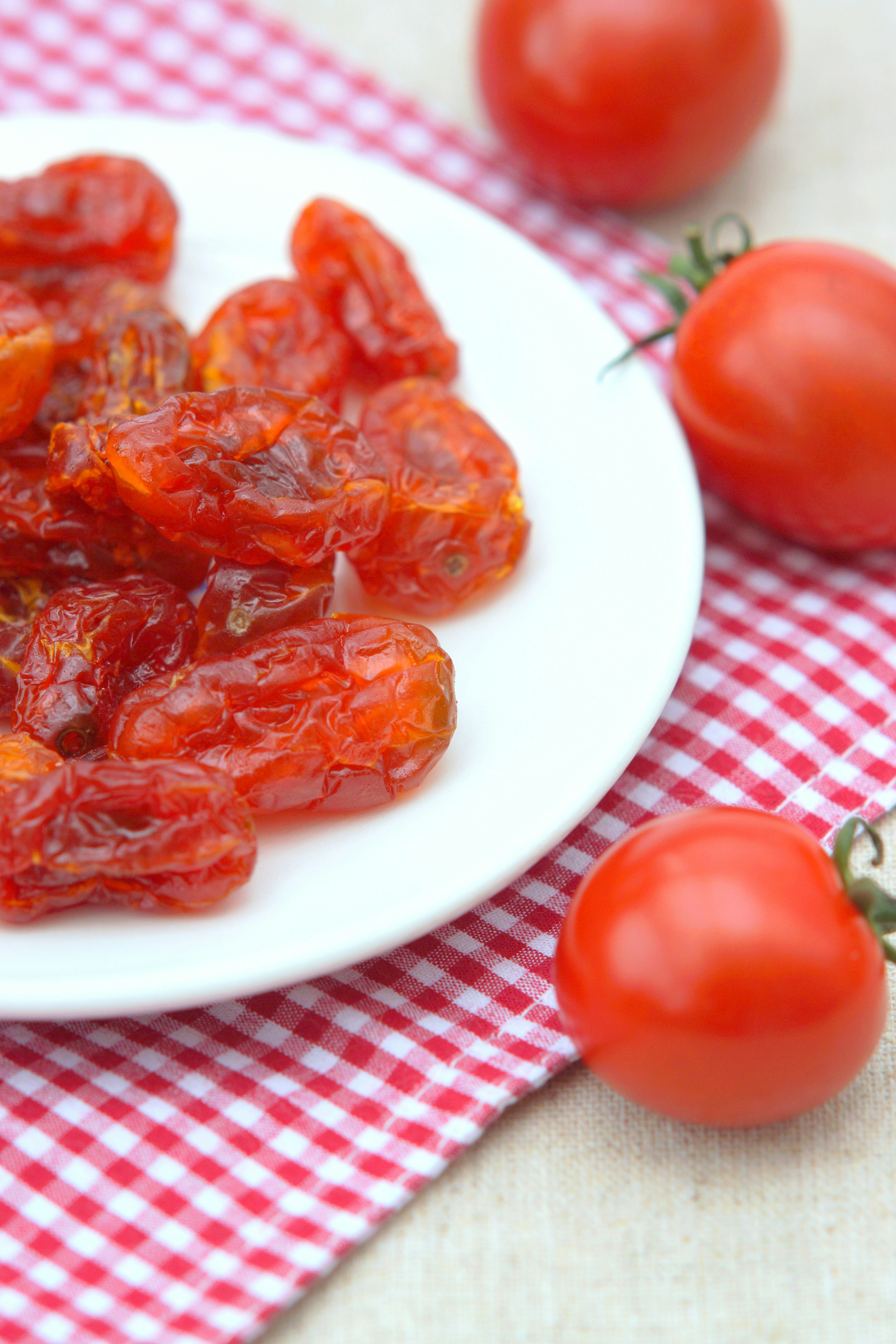 Tomates secas en un plato con tomates rojos frescos cerca