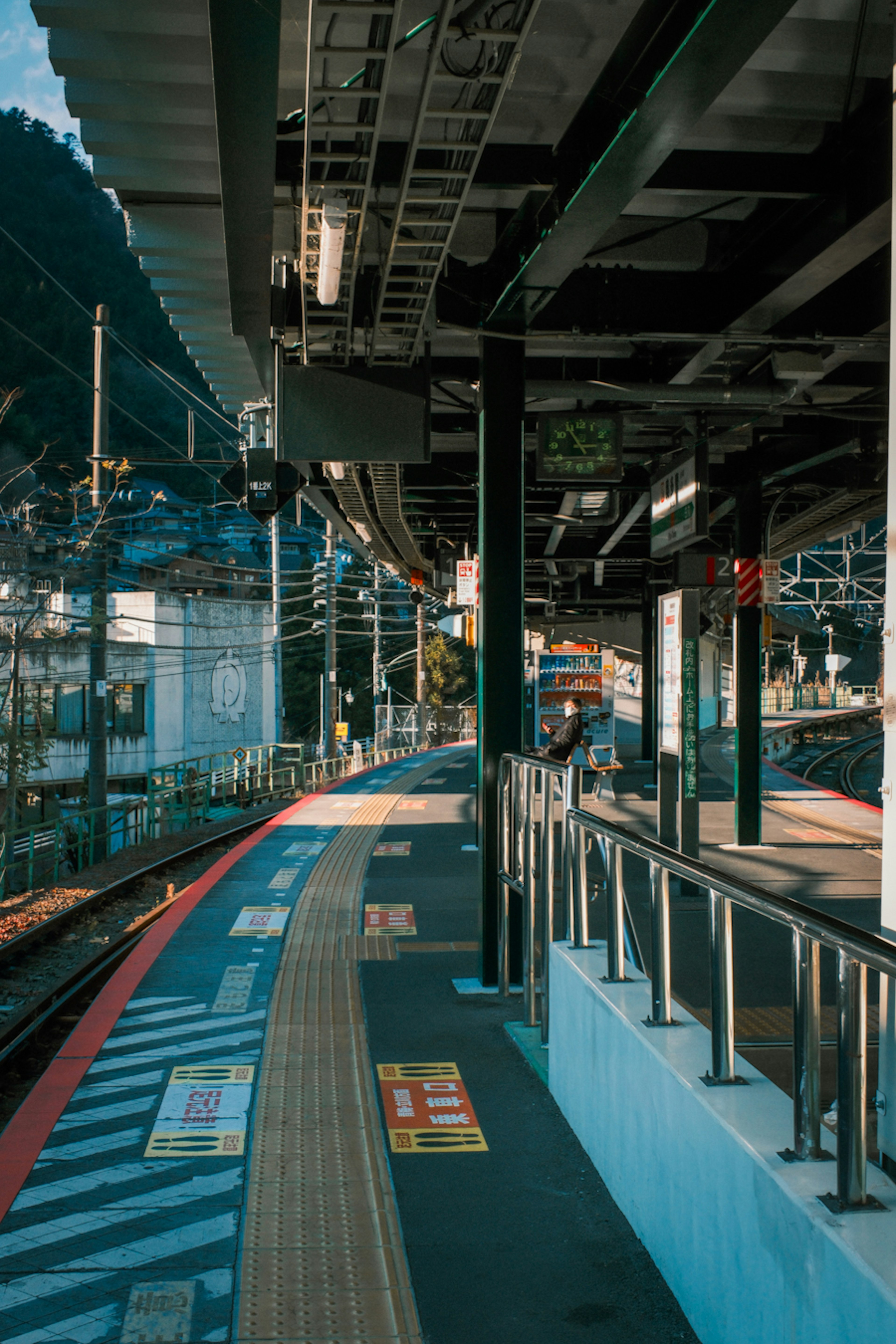 Ruhige Bahnhofplattform mit Gleisen und Berg im Hintergrund