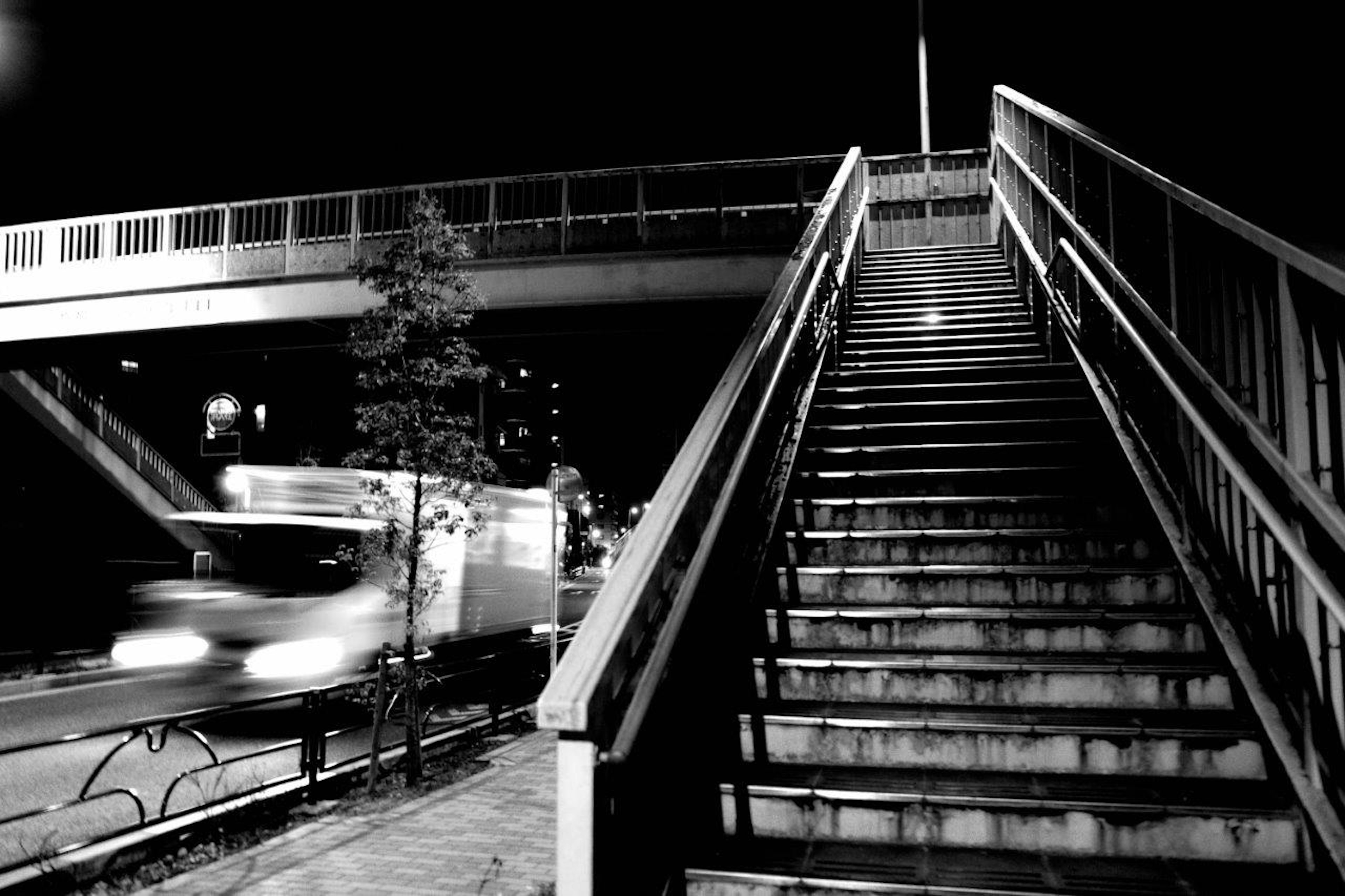 Fotografía en blanco y negro de una escalera y un paso elevado de noche