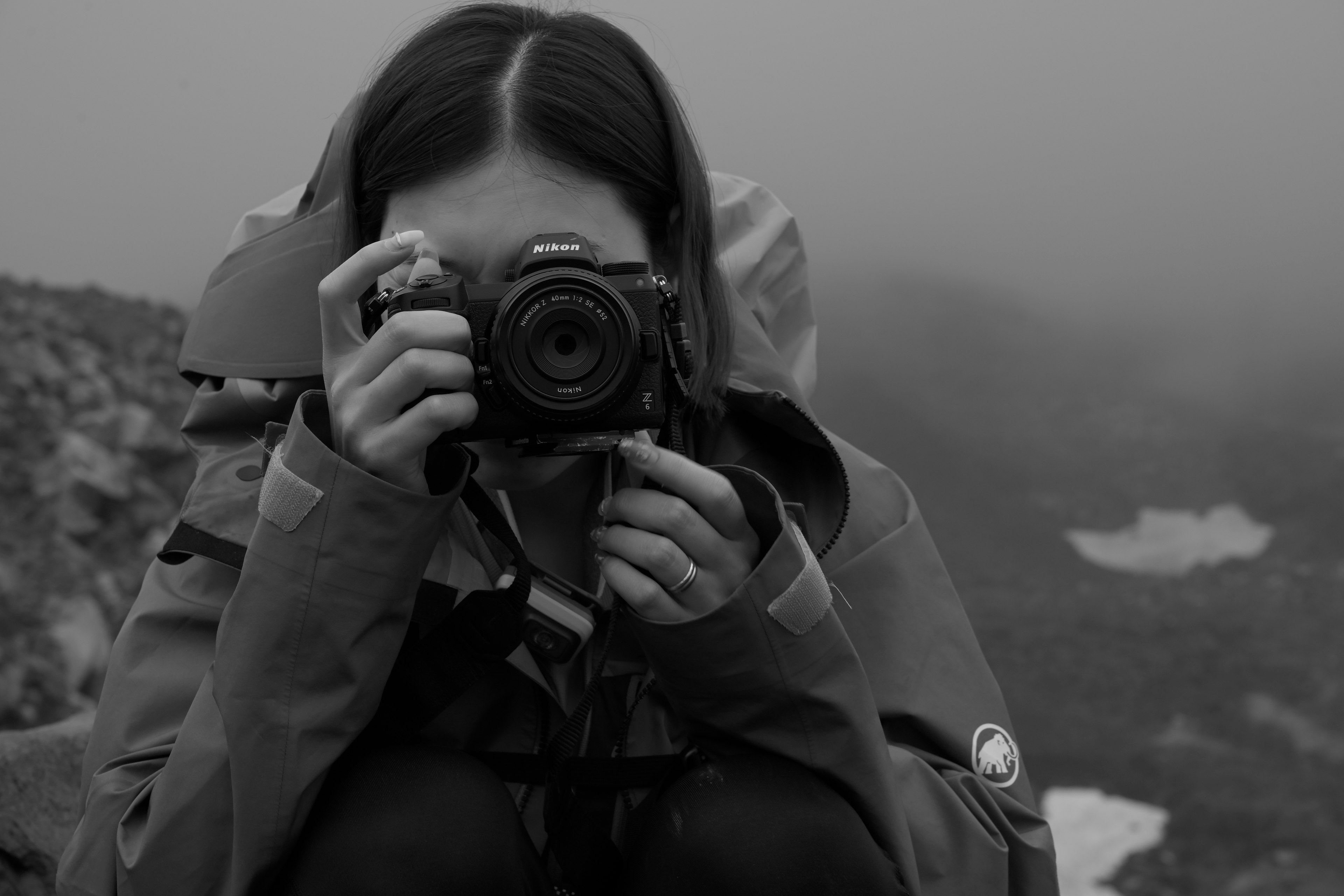 Black and white photo of a woman holding a camera in the fog