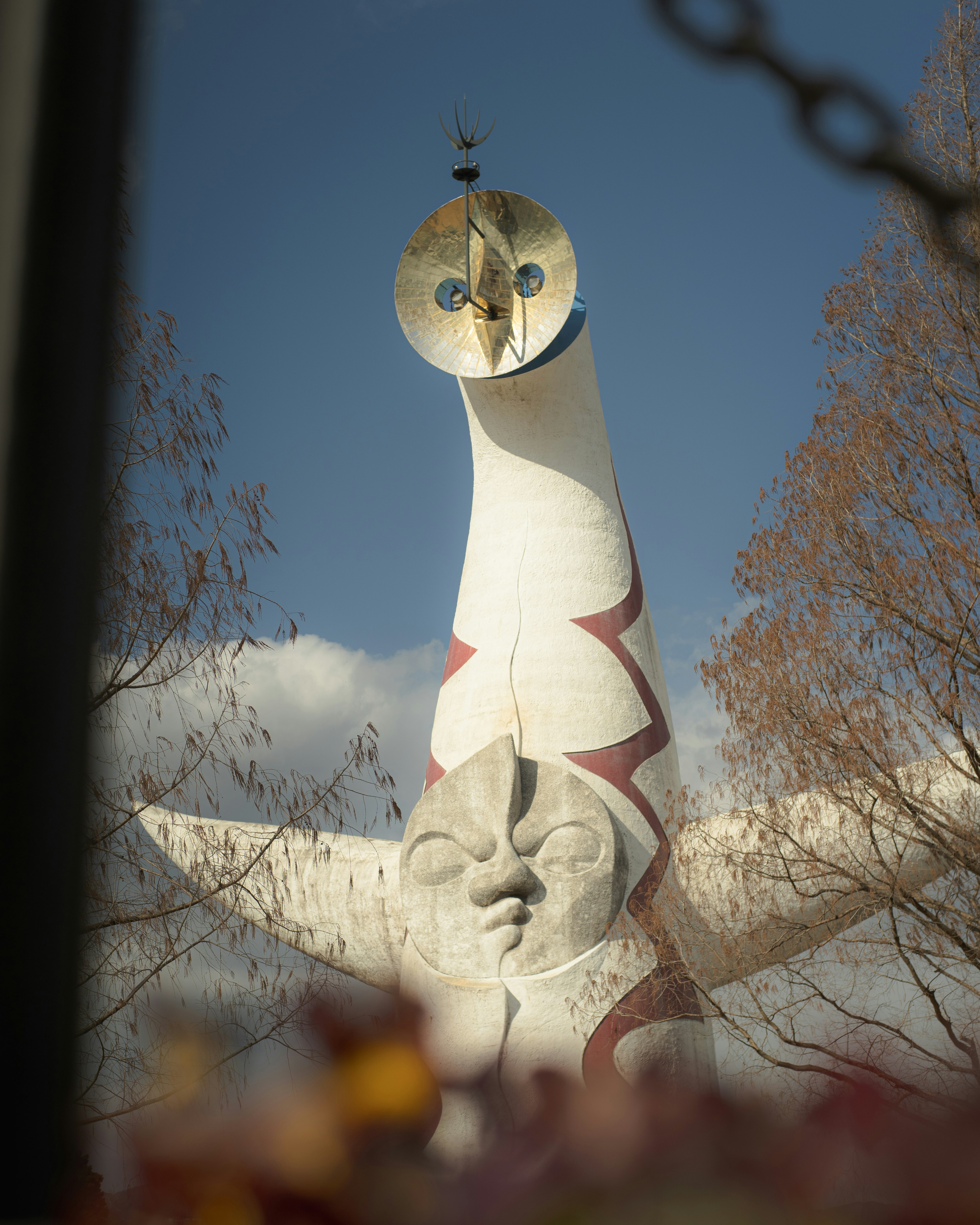 Ein hoher Monument mit einem einzigartigen Design, das ein Gesicht und ein sonnenähnliches Element im Hintergrund zeigt