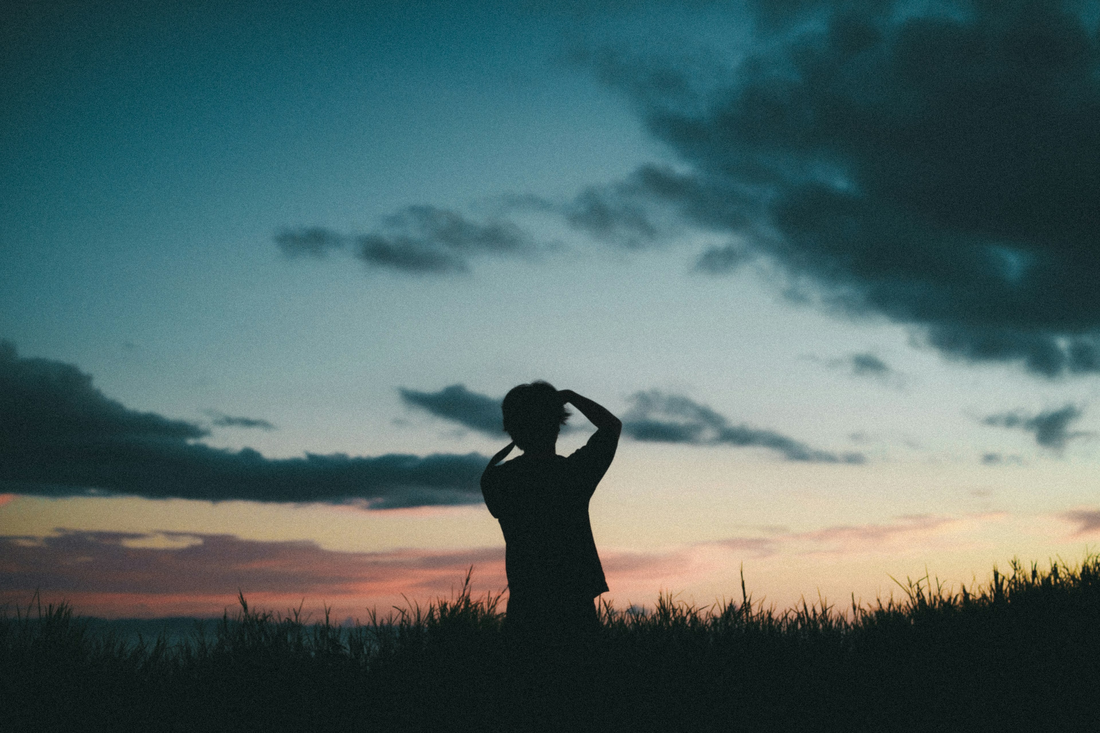 Silhouette seseorang yang berpose di latar belakang langit senja