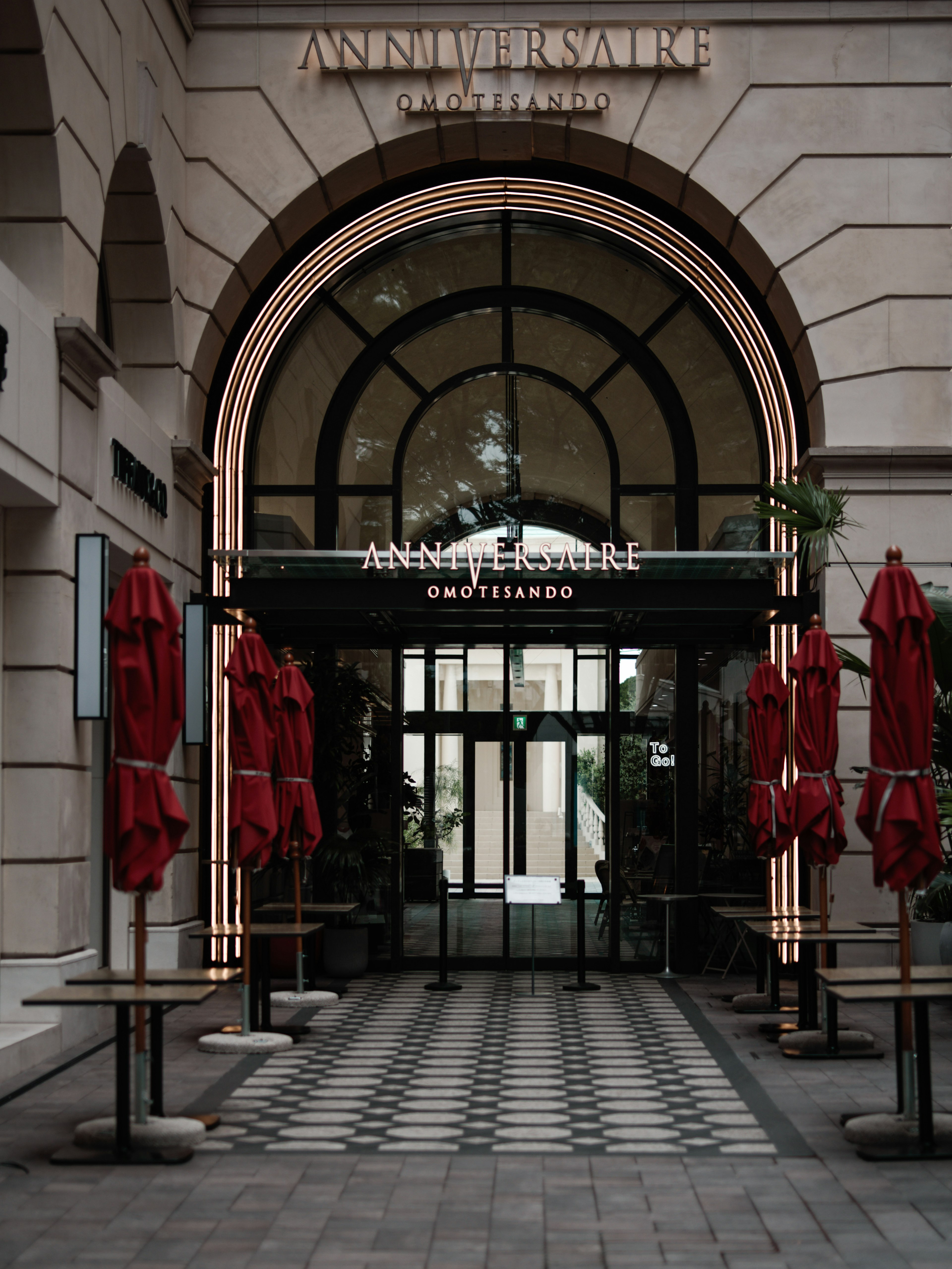 Cafe entrance with red umbrellas and an arched doorway design