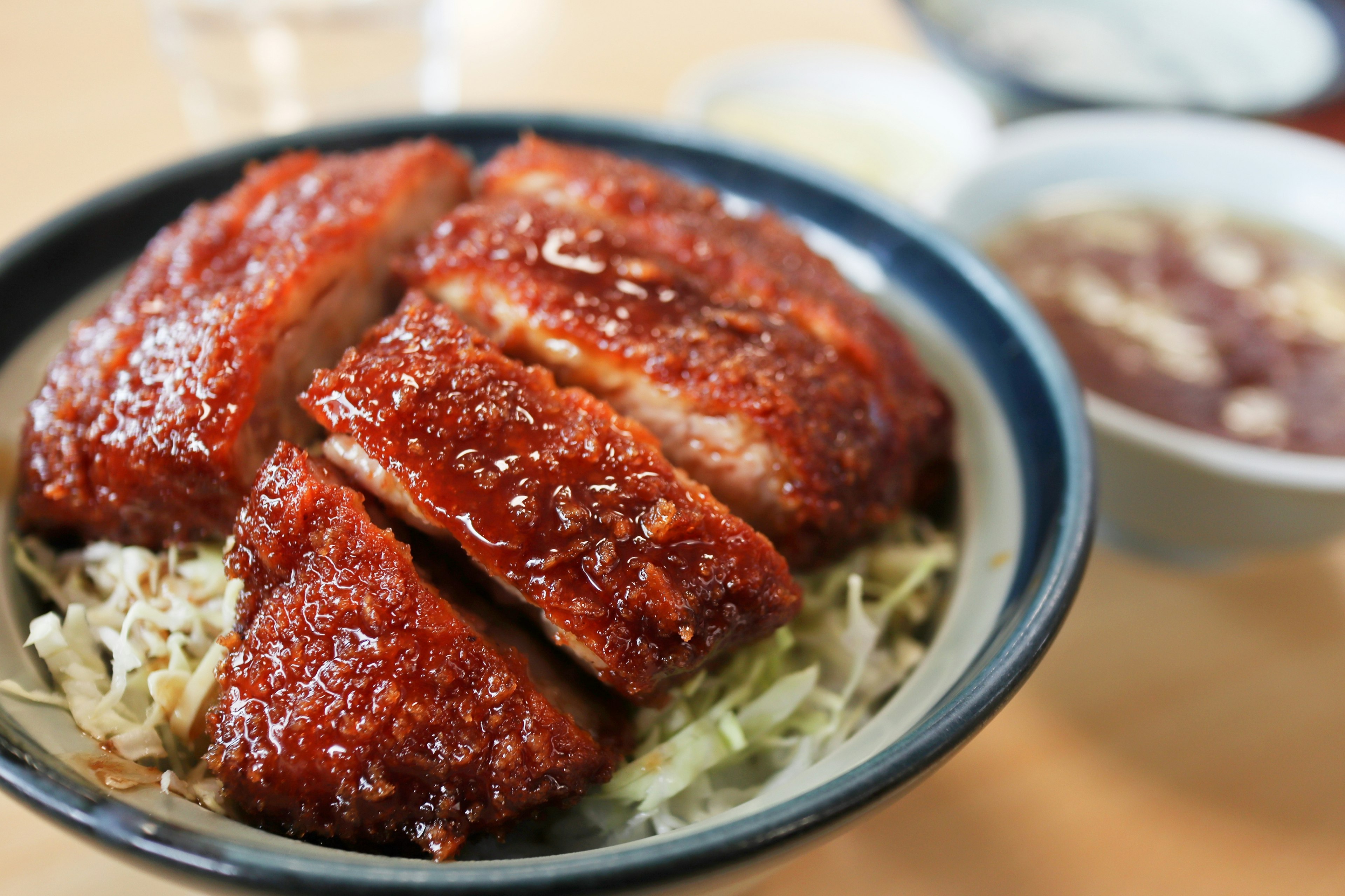 A bowl of katsudon featuring glossy pork cutlet and shredded cabbage