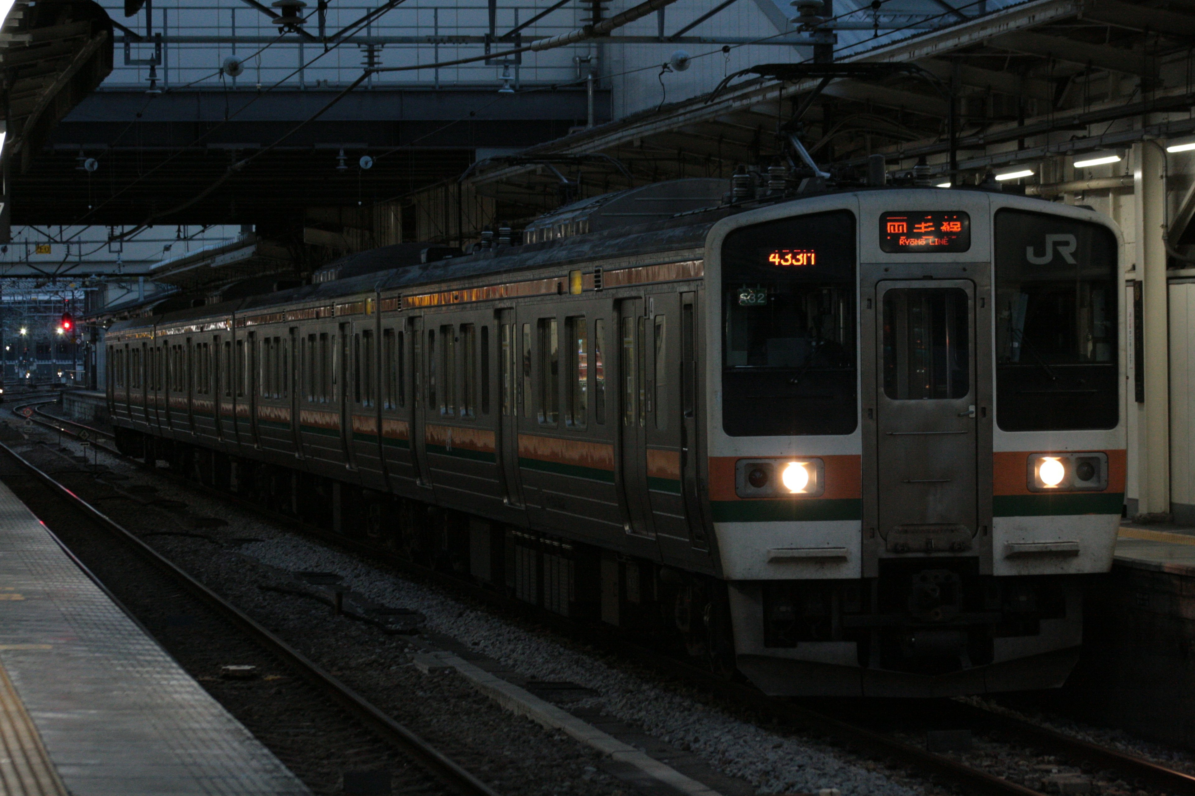 Treno JR fermo in una stazione poco illuminata con luci accese