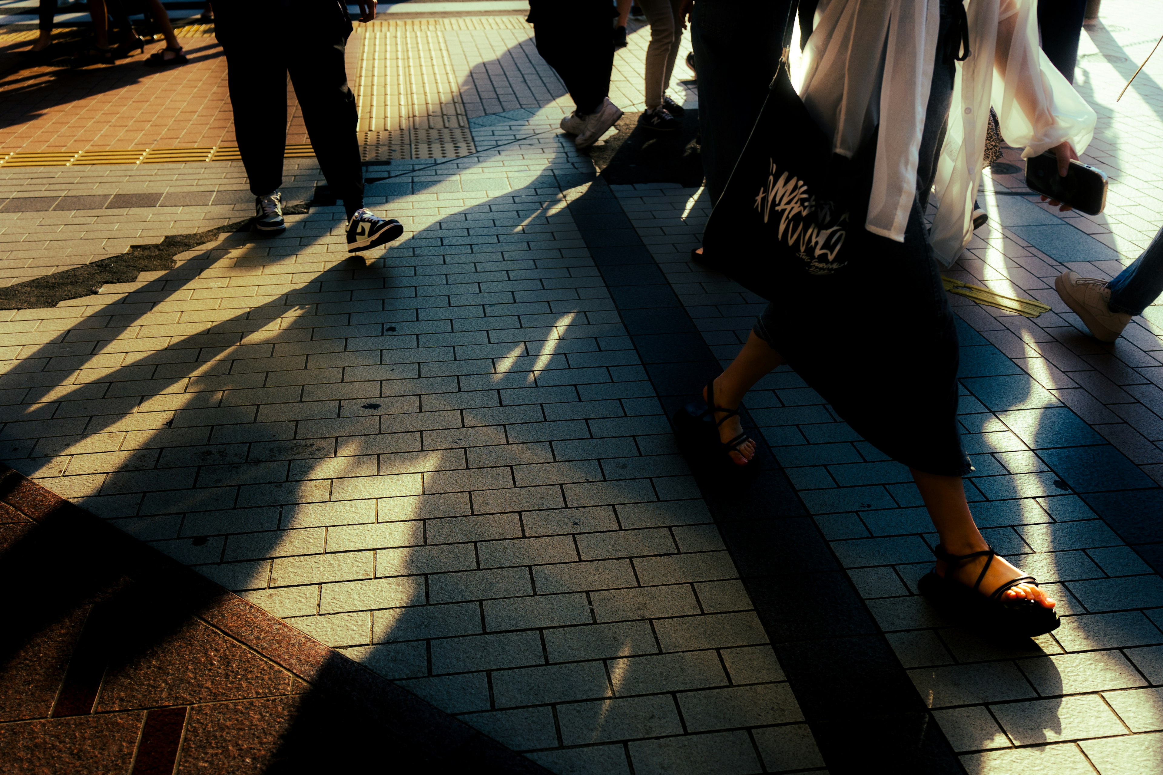 Urban scene featuring shadows of people walking and intricate tile patterns