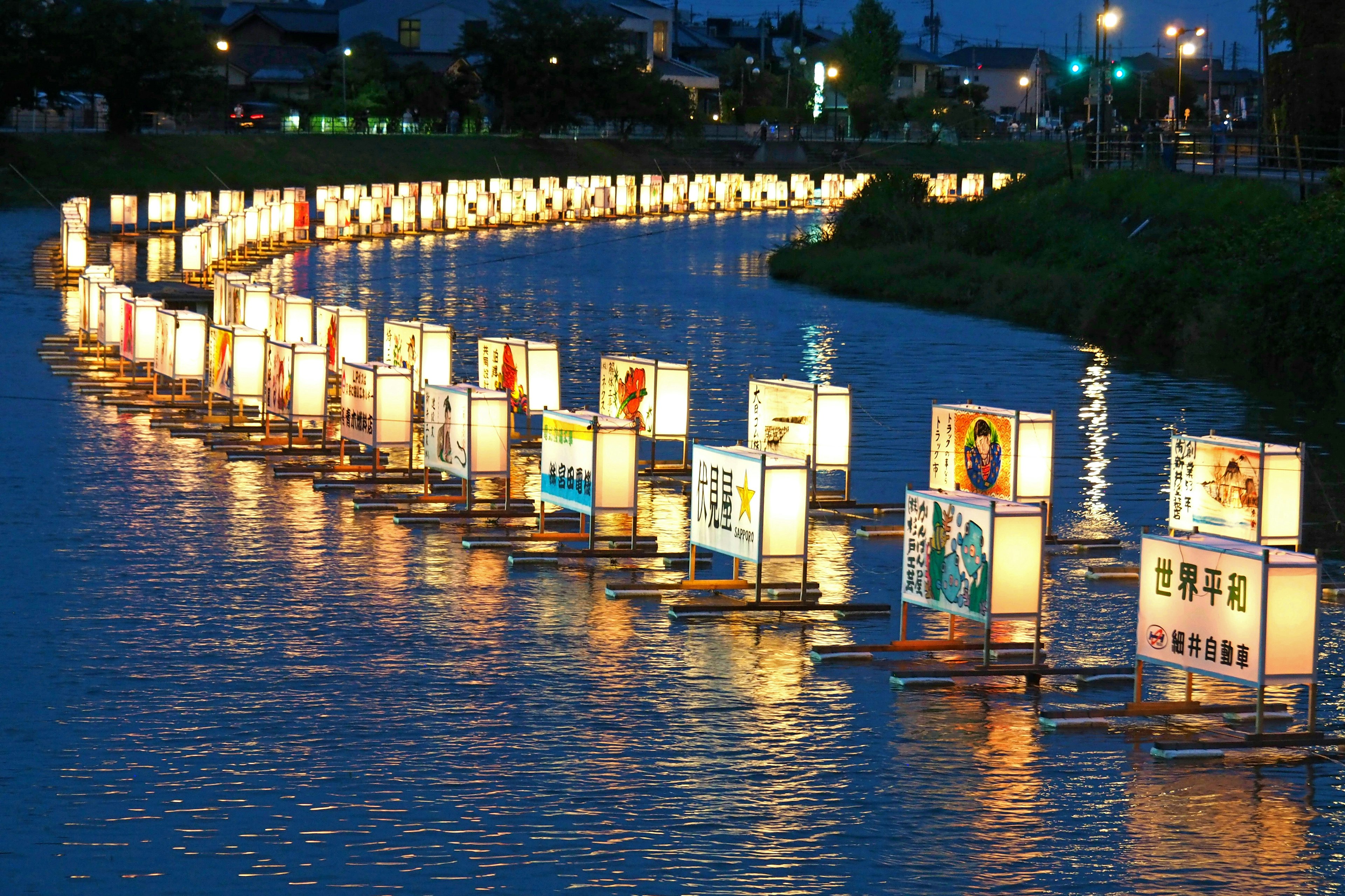 A beautiful row of lanterns floating on a river at night