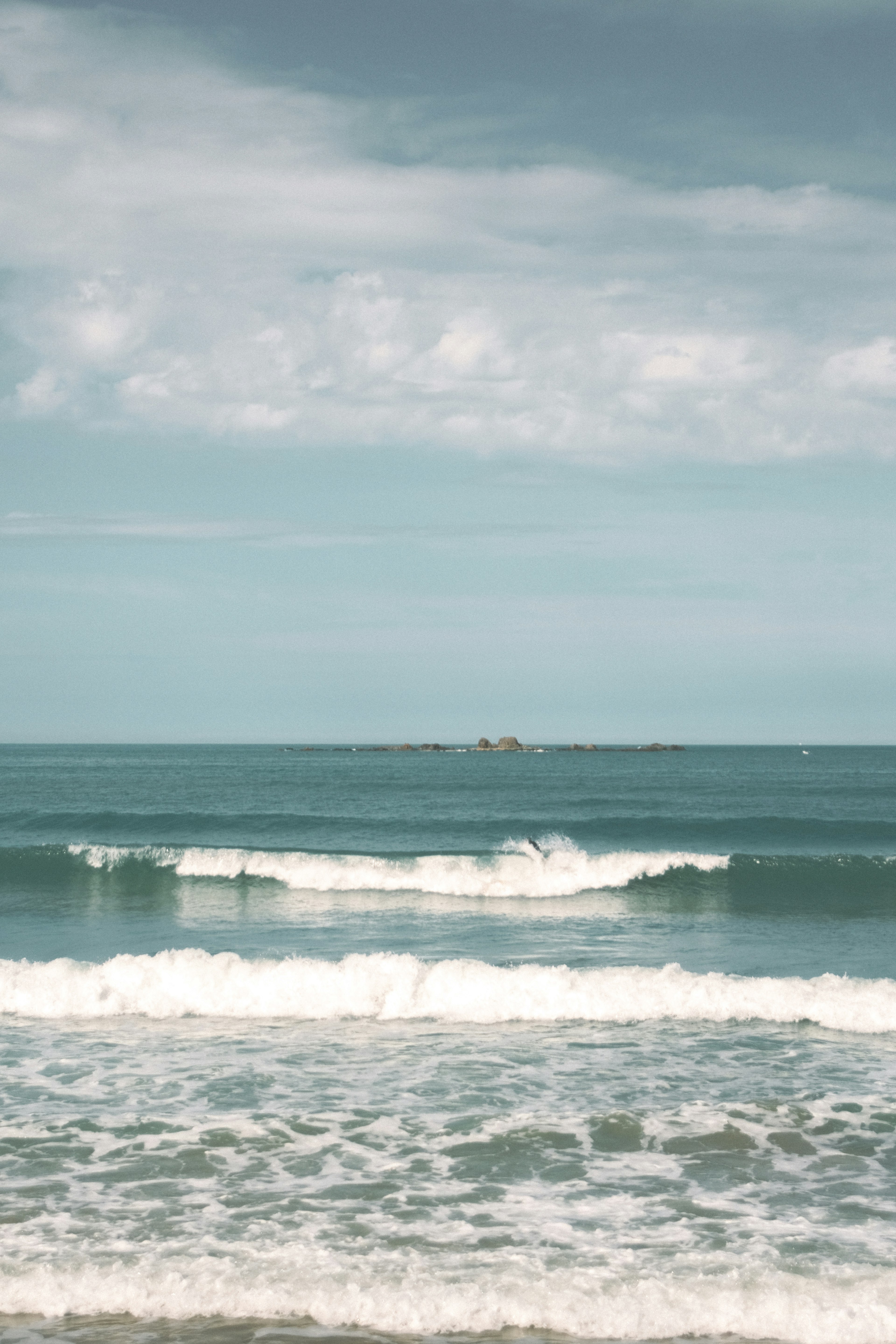 Calm ocean waves with a blue sky and clouds