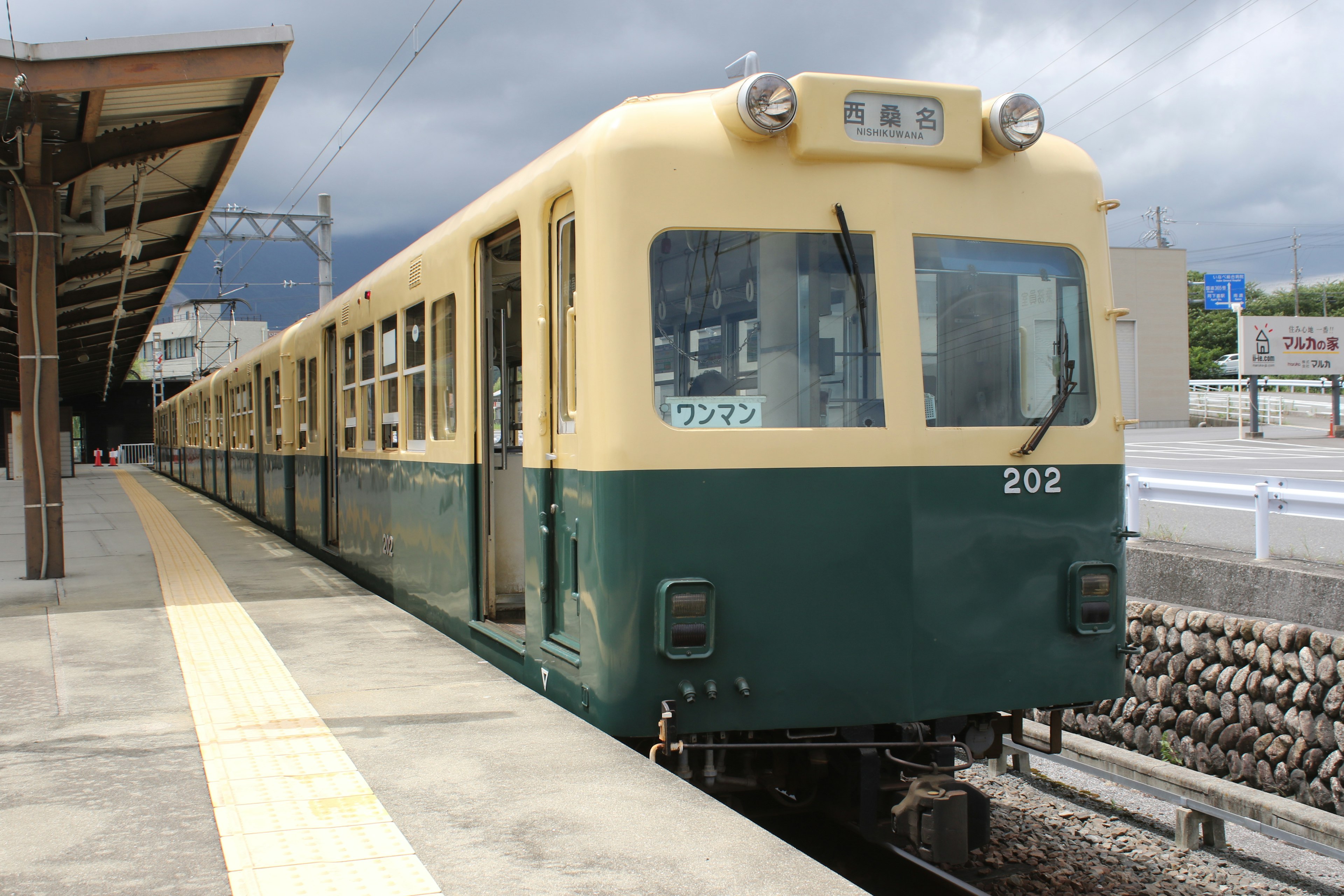 緑とクリーム色の電車が駅に停車している風景