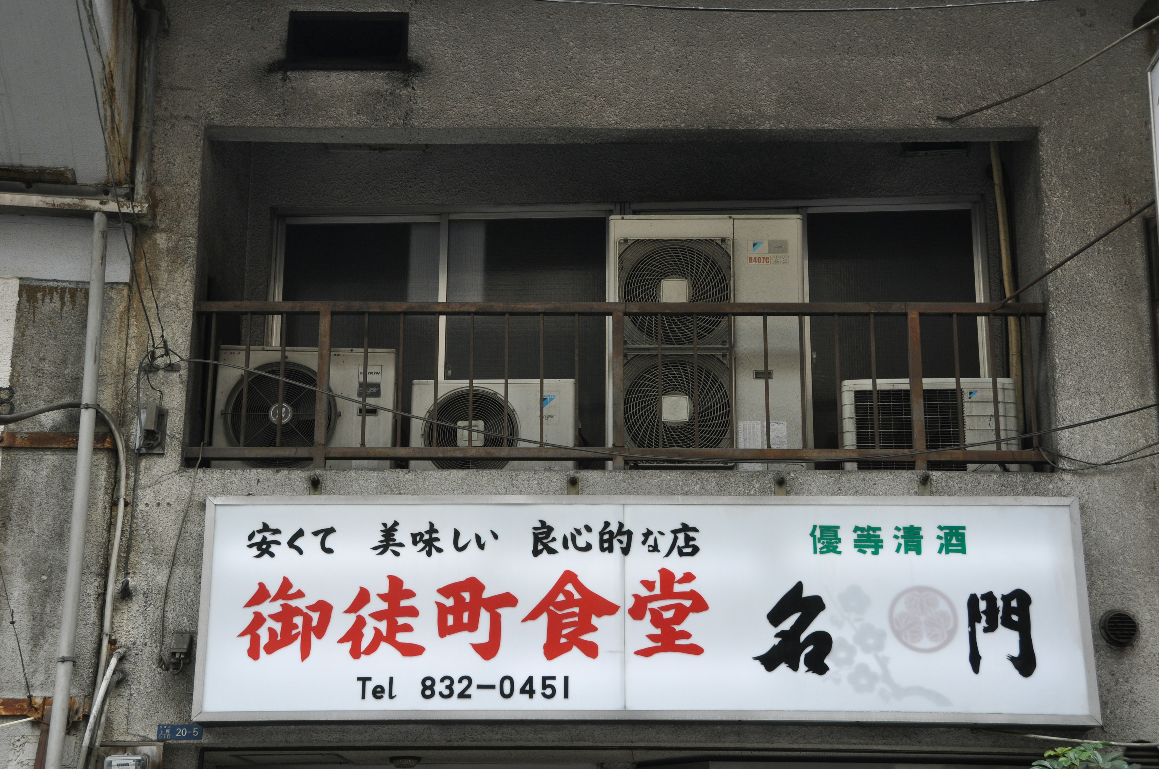 Sign of a dining establishment on an old building with air conditioning units