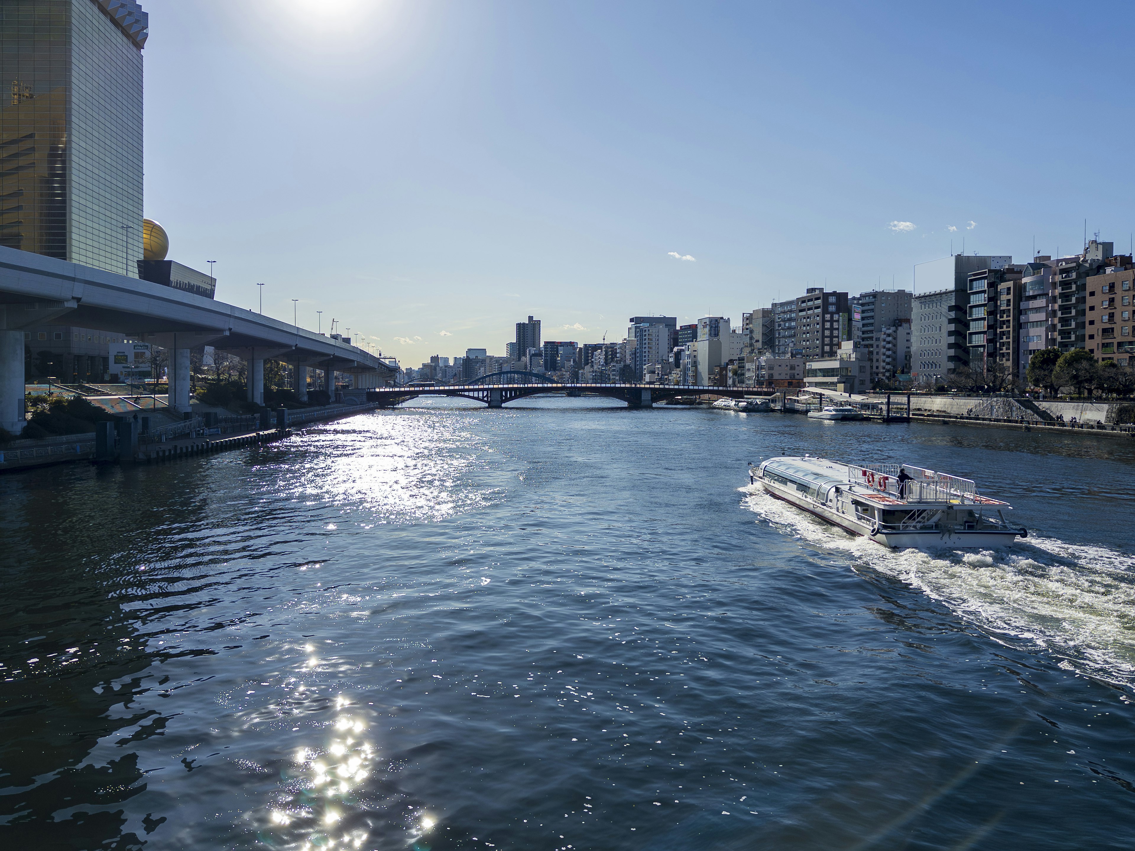 Una vista clara de un barco navegando por el río con un paisaje urbano de fondo