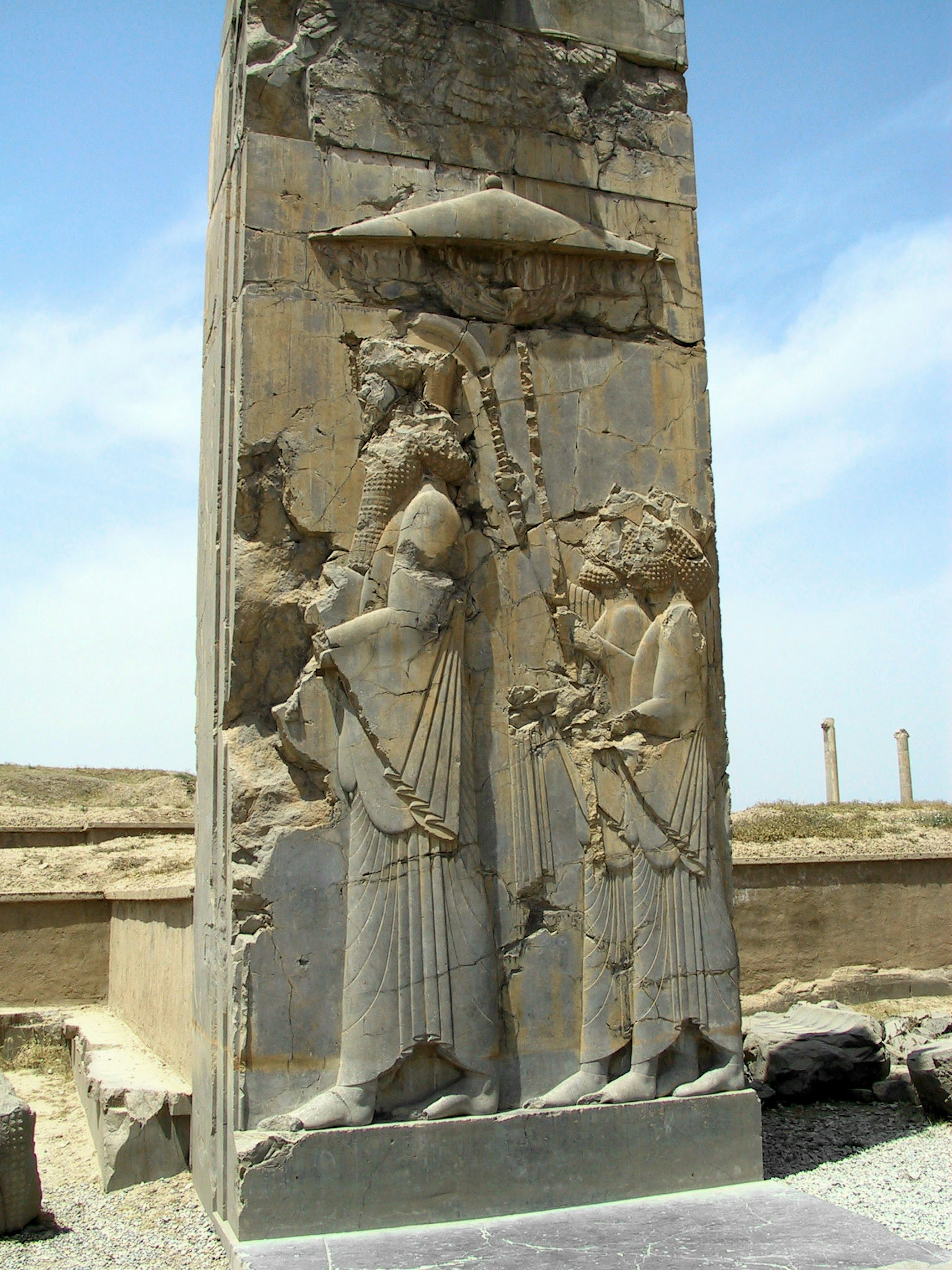 Ancient Persian carved stone pillar featuring a standing woman and a child