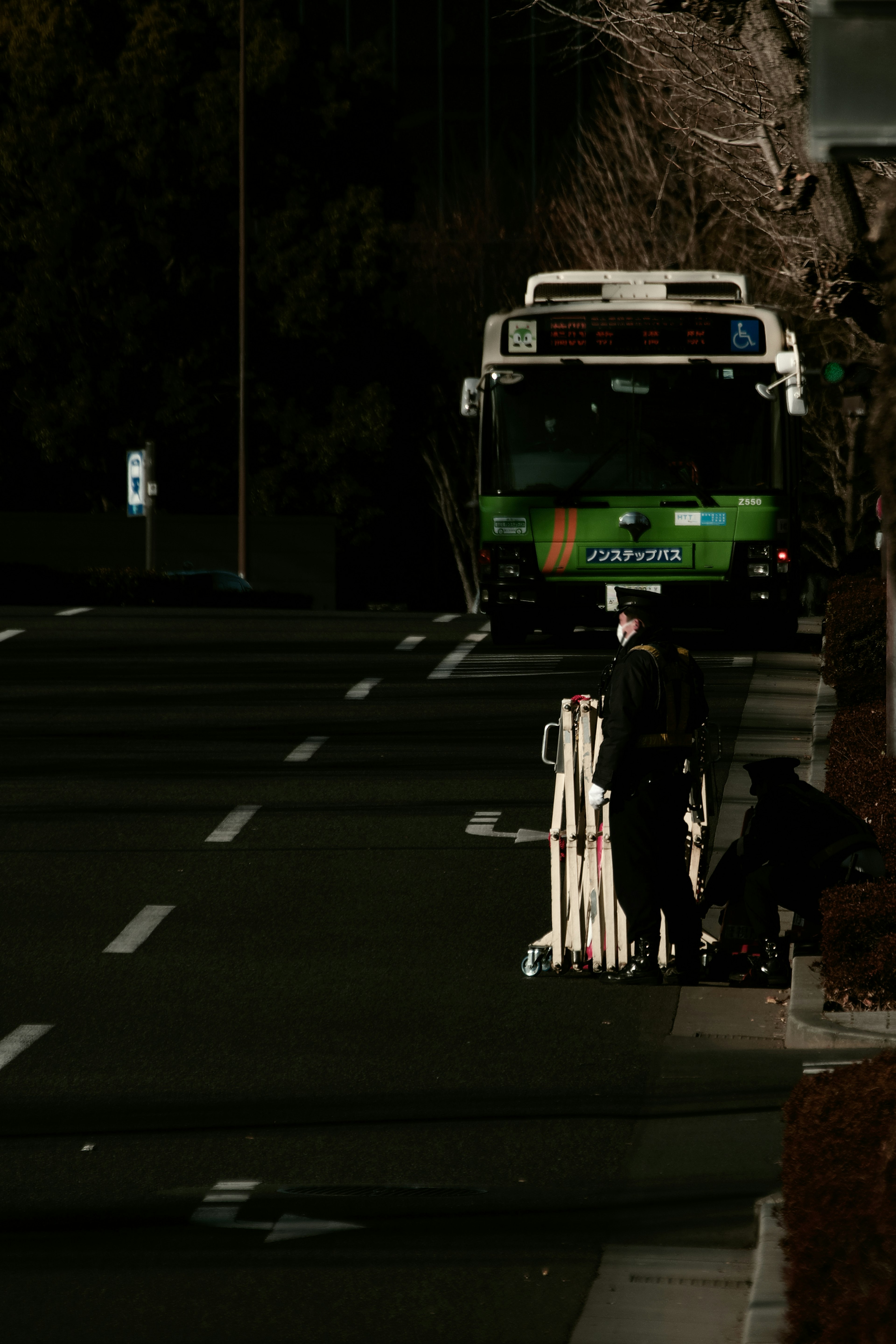 在黑暗道路上站着的警察和绿色公交车