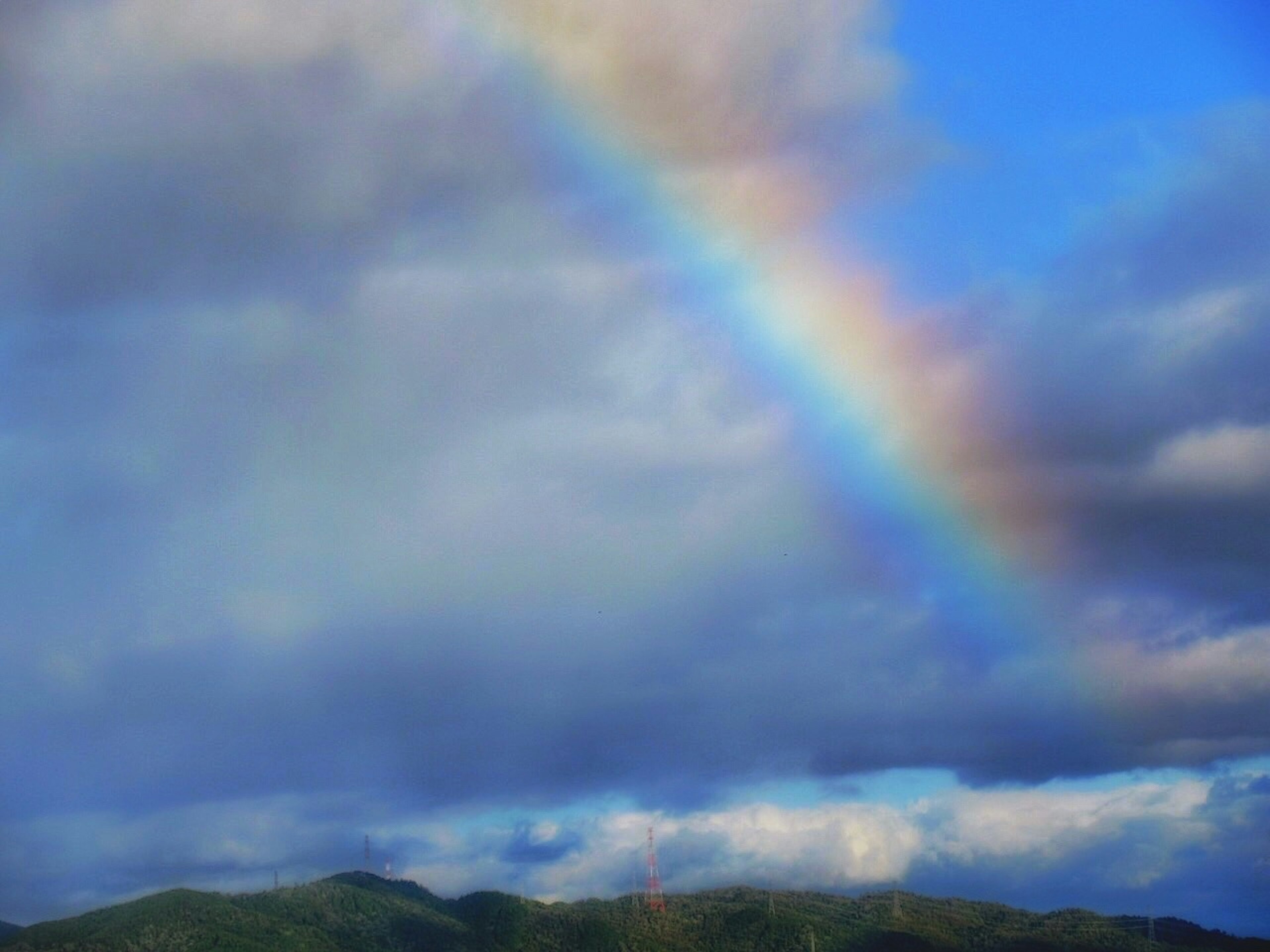 Rainbow arching across a blue sky filled with clouds