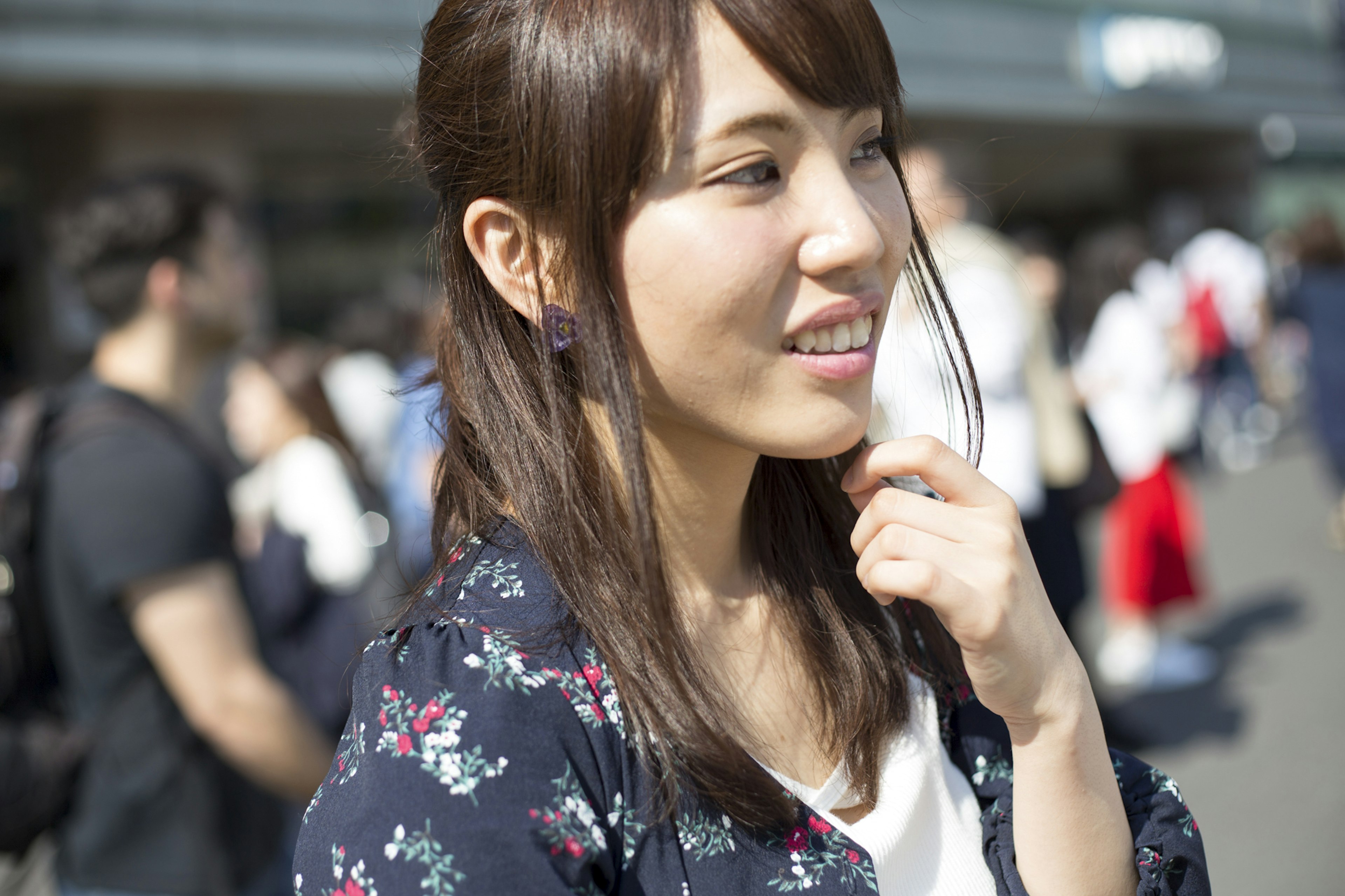 A woman smiling and contemplating with people in line in the background