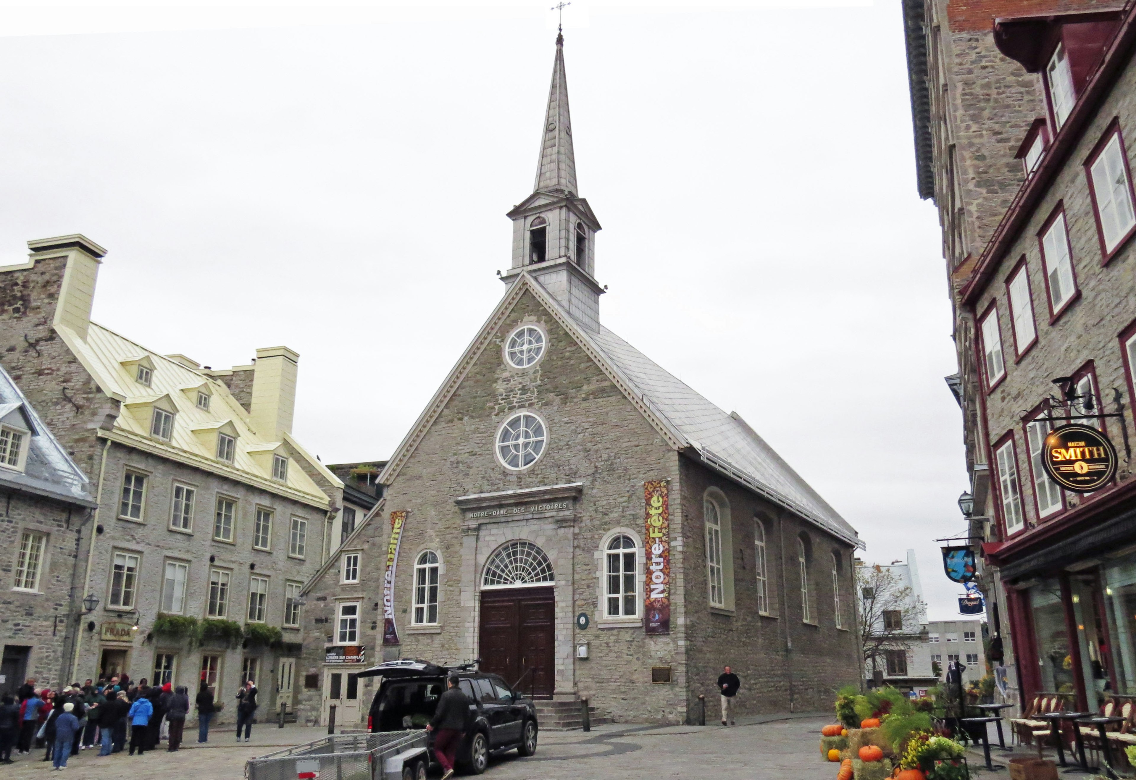 Église en pierre avec un clocher élancé entourée de bâtiments historiques