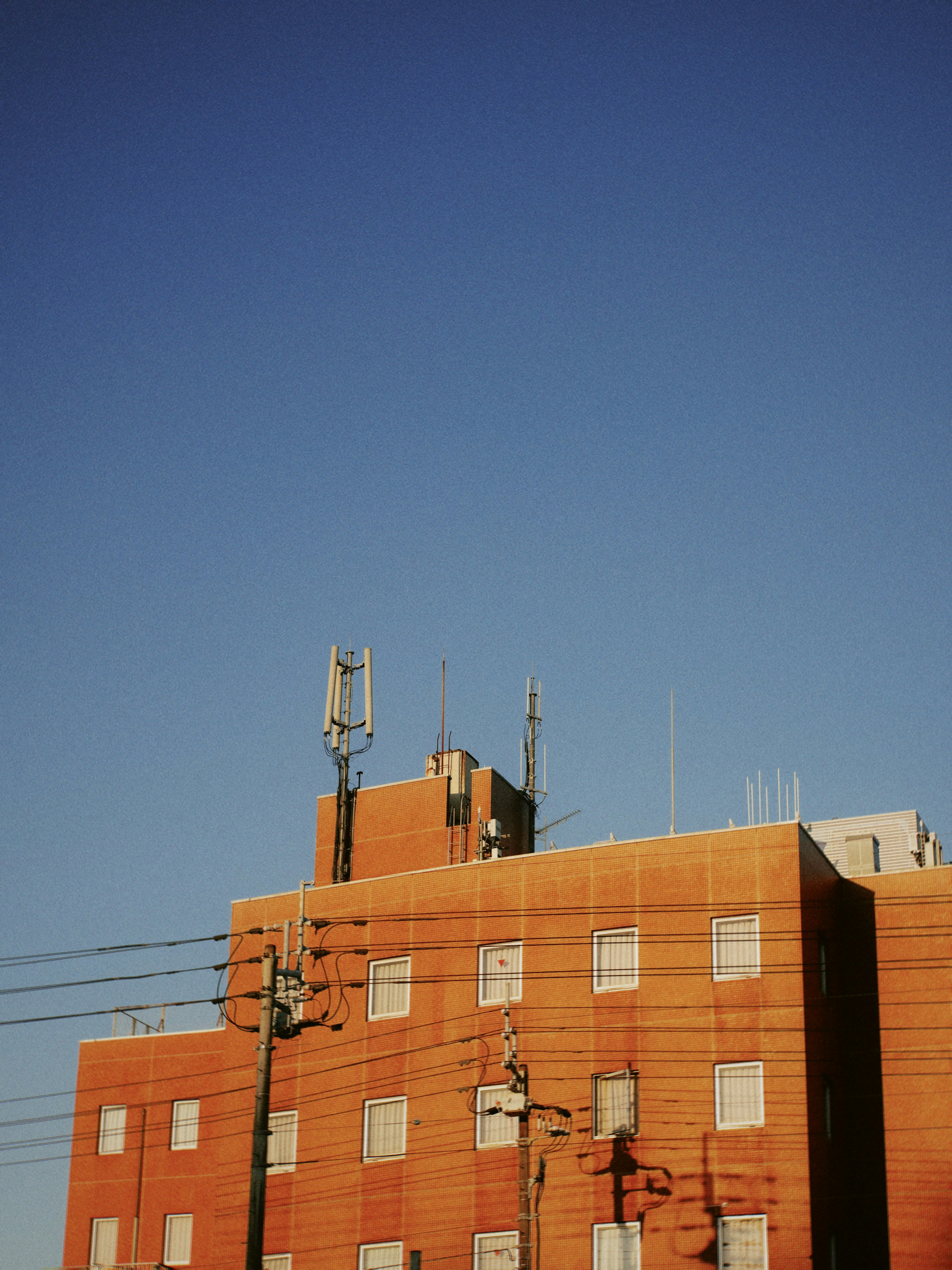 Bâtiment orange avec des antennes de communication sous un ciel bleu