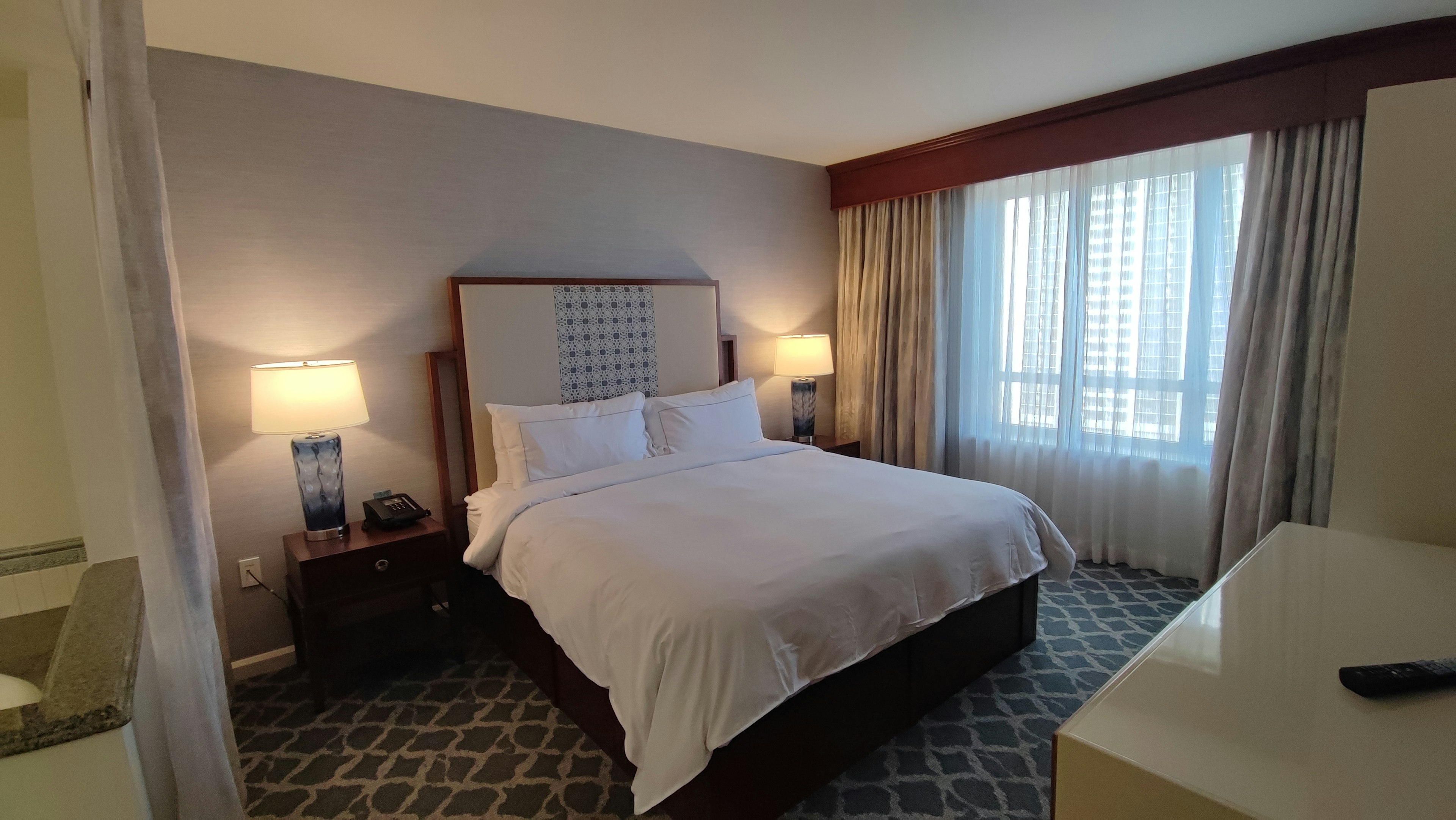 Modern hotel room featuring a large bed and bright windows