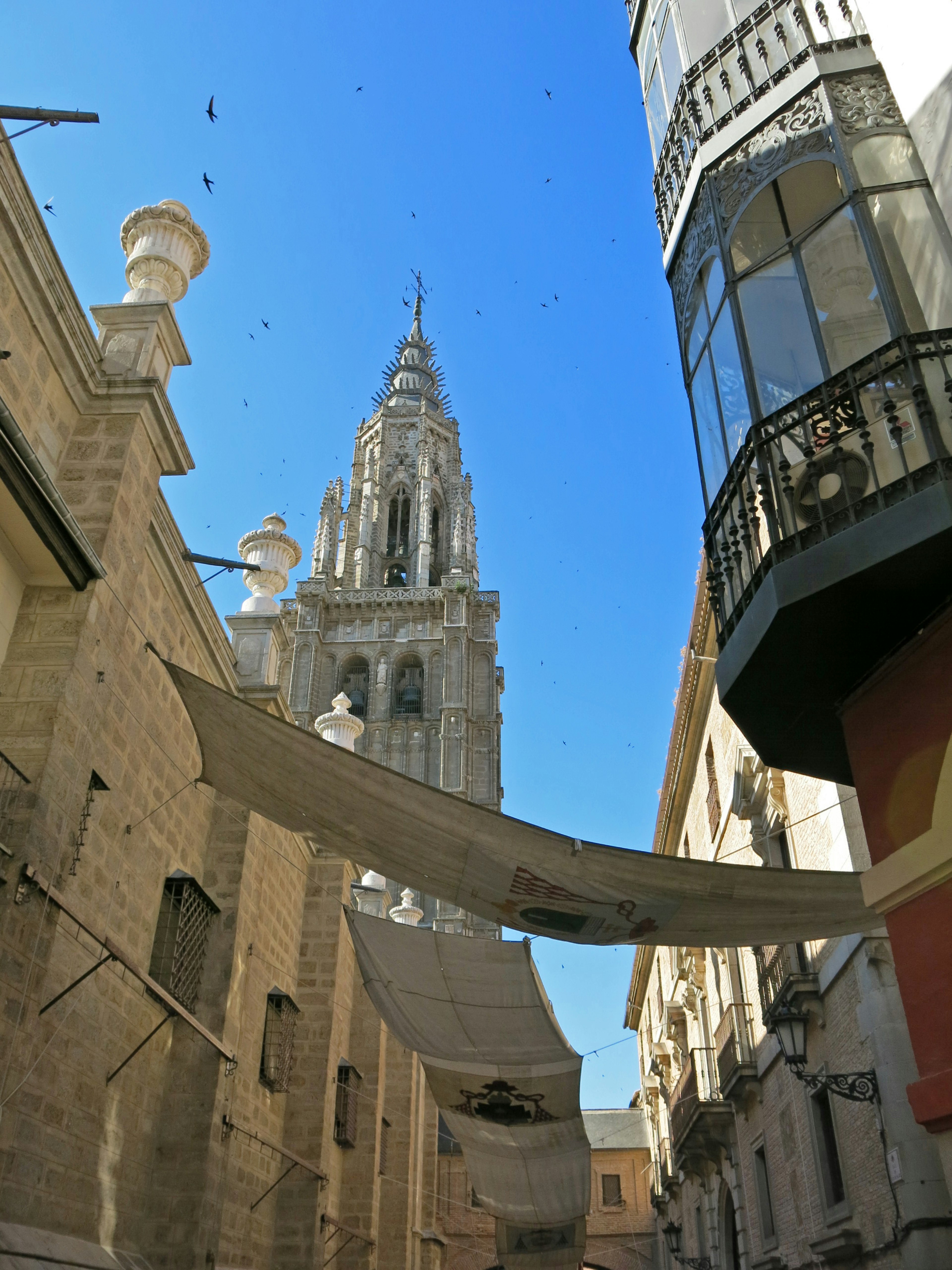 Rue étroite avec des bâtiments historiques et un clocher sous un ciel bleu clair