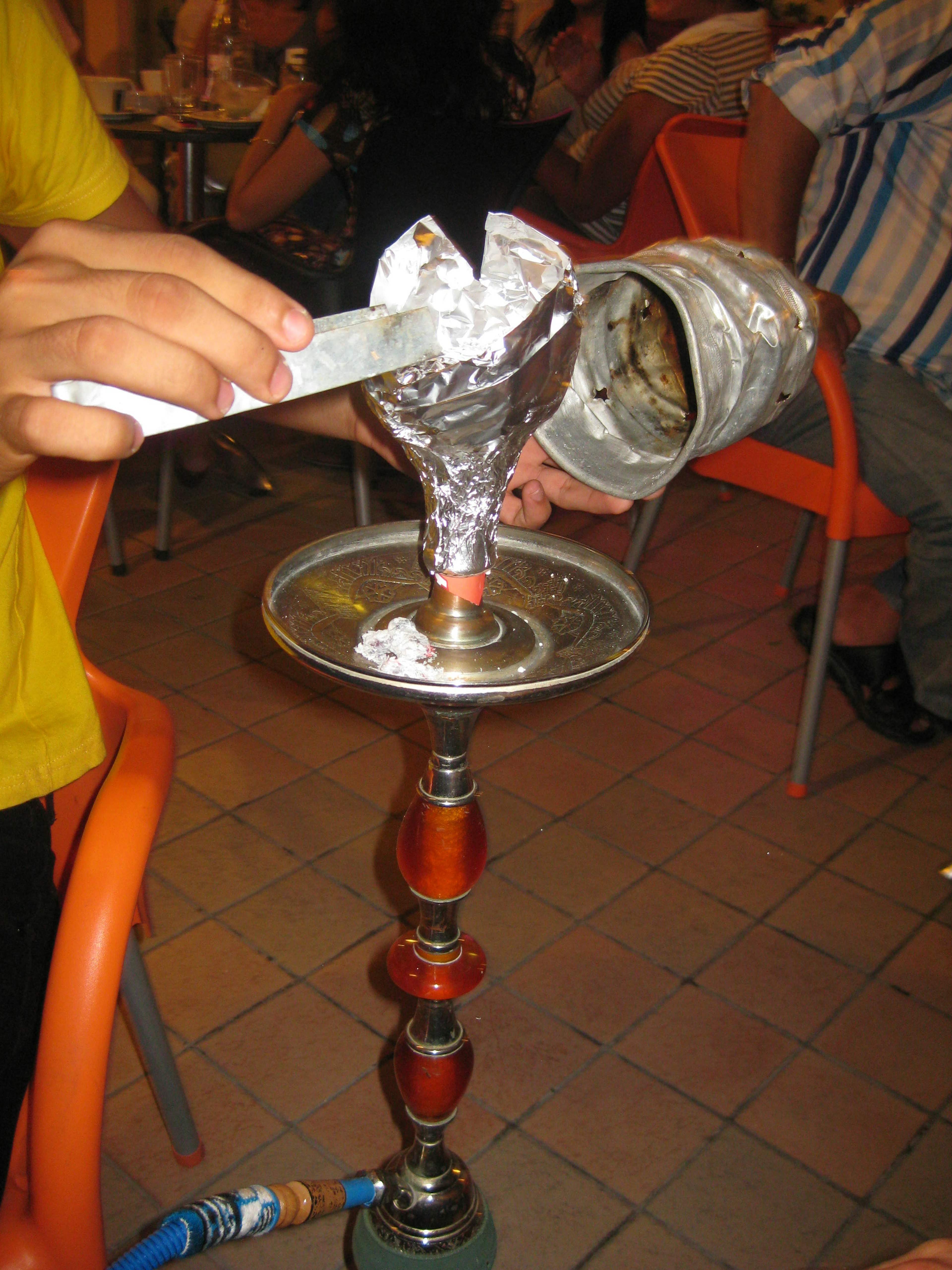 A person preparing a fruit-flavored hookah with aluminum foil