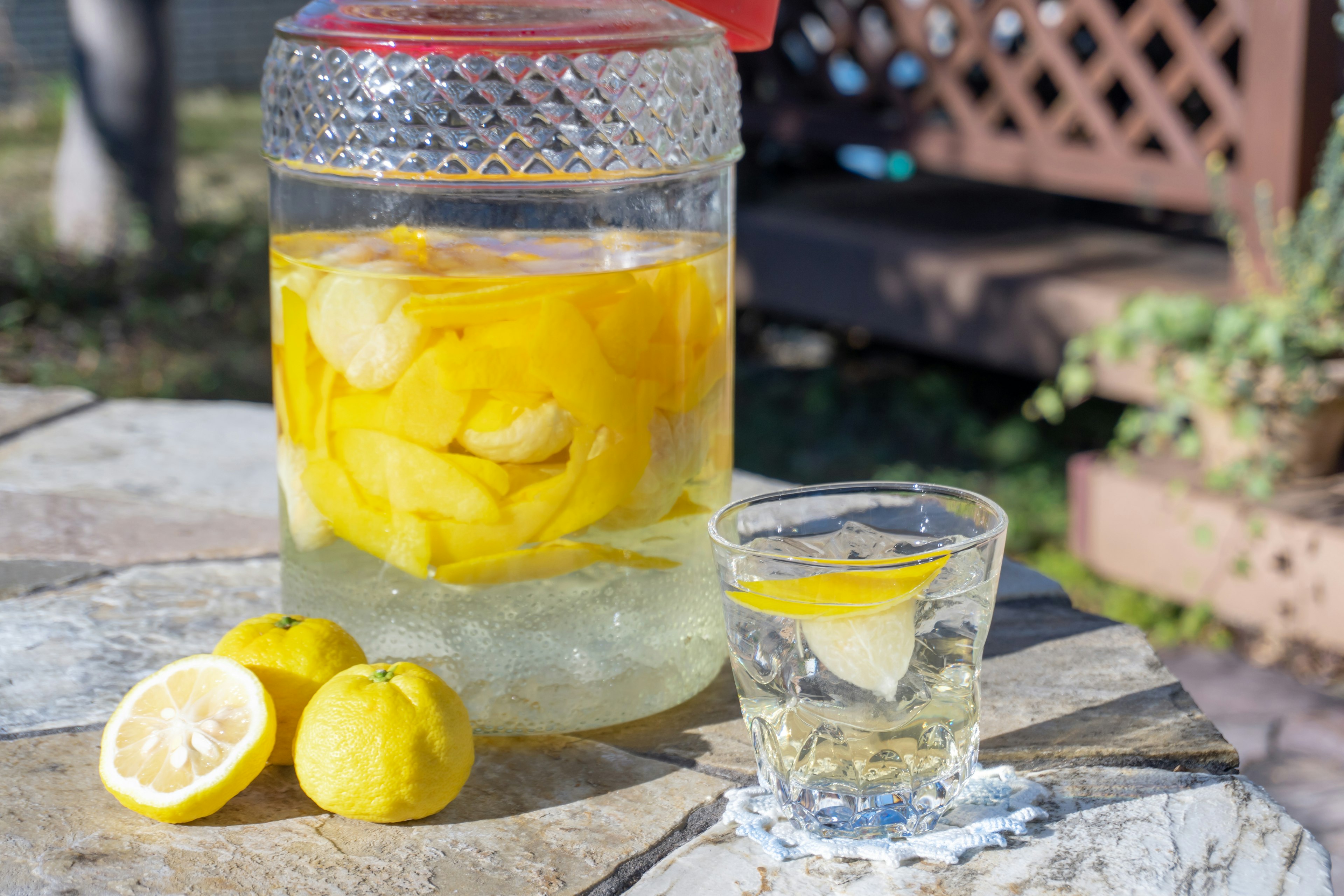 Immagine di una caraffa piena di fette di limone e di un bicchiere di limonata