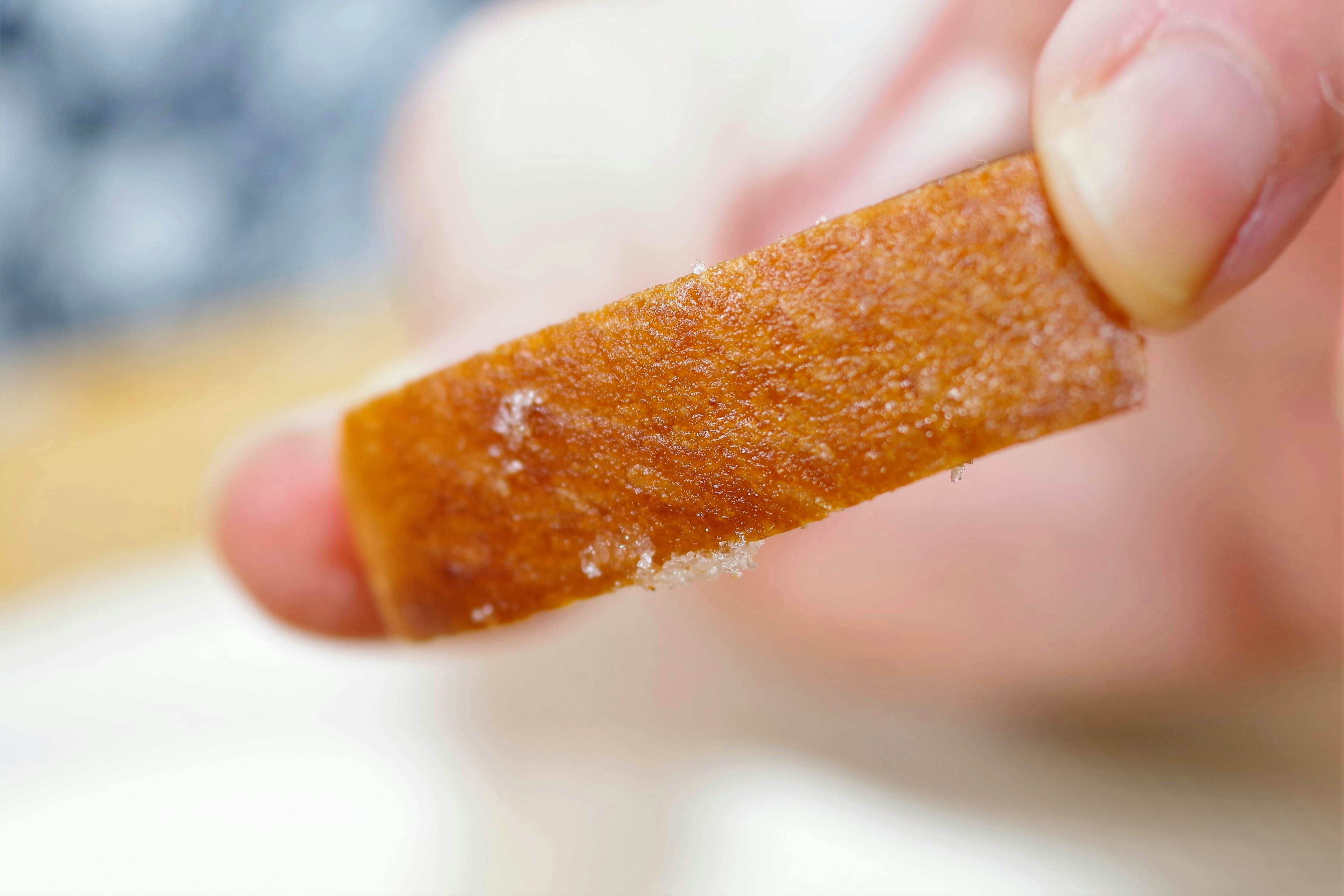 A piece of brown candy held between fingers