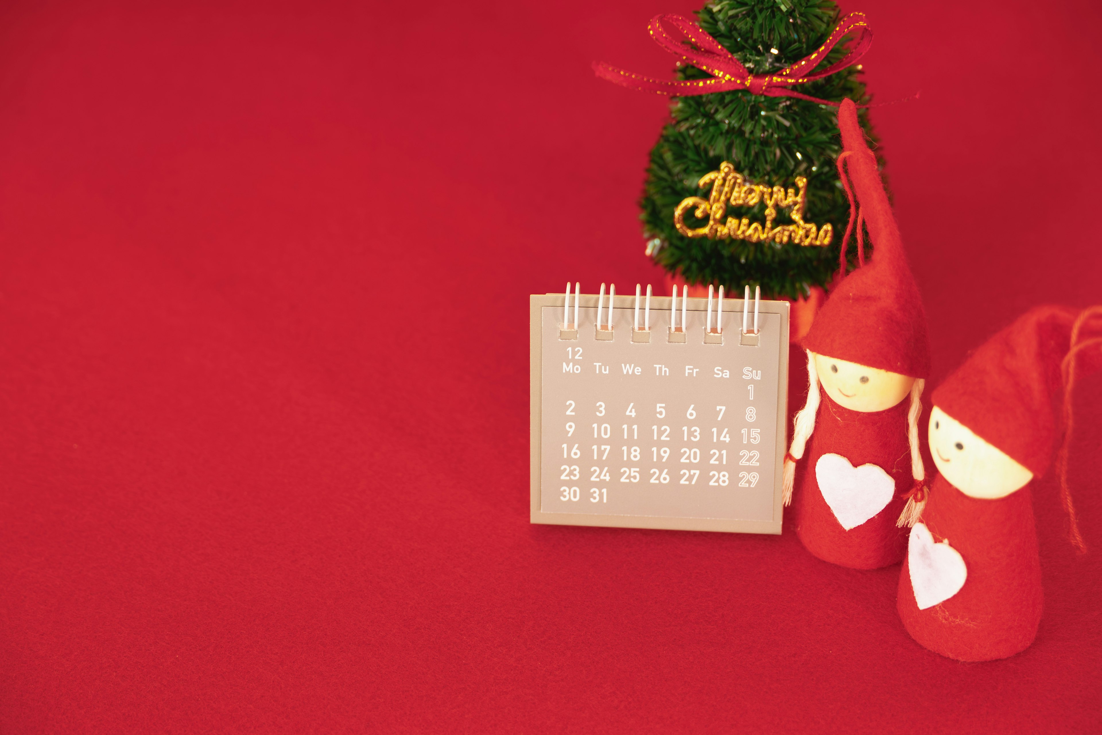 Un pequeño calendario y decoraciones navideñas sobre un fondo rojo