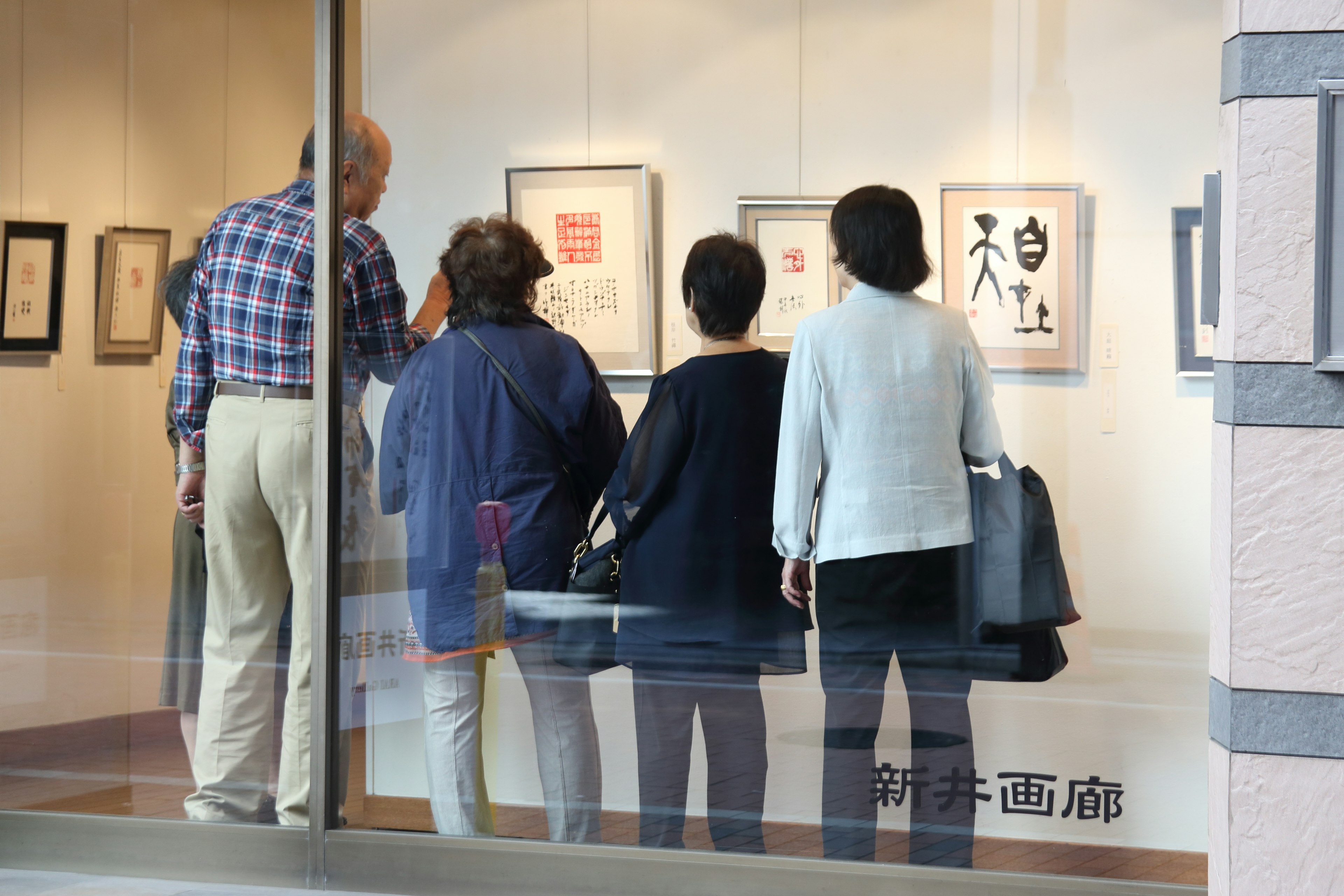 People viewing art pieces through a gallery window