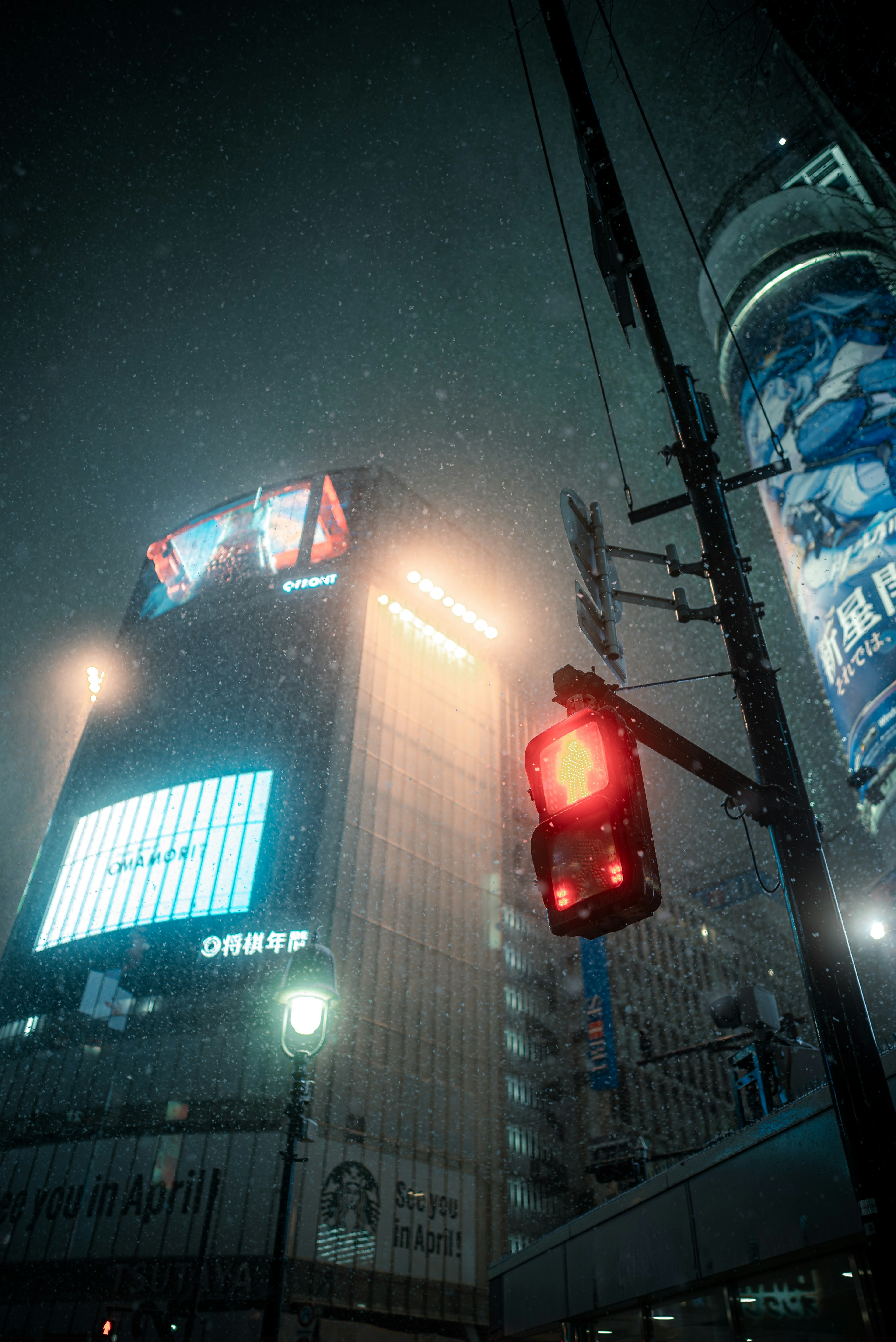 Urban landscape featuring a red traffic light and illuminated buildings in fog