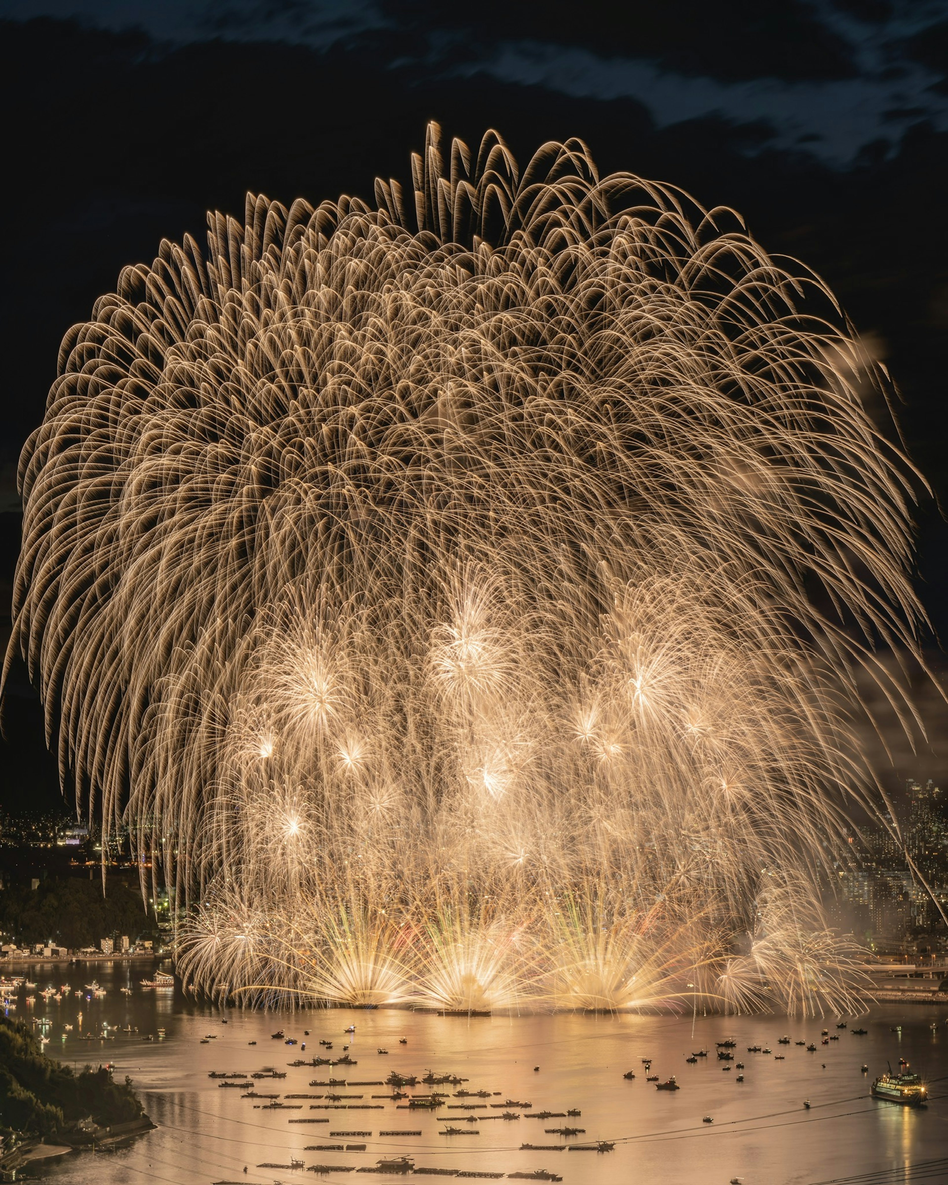 A beautiful scene of golden fireworks exploding in the night sky reflecting on the water