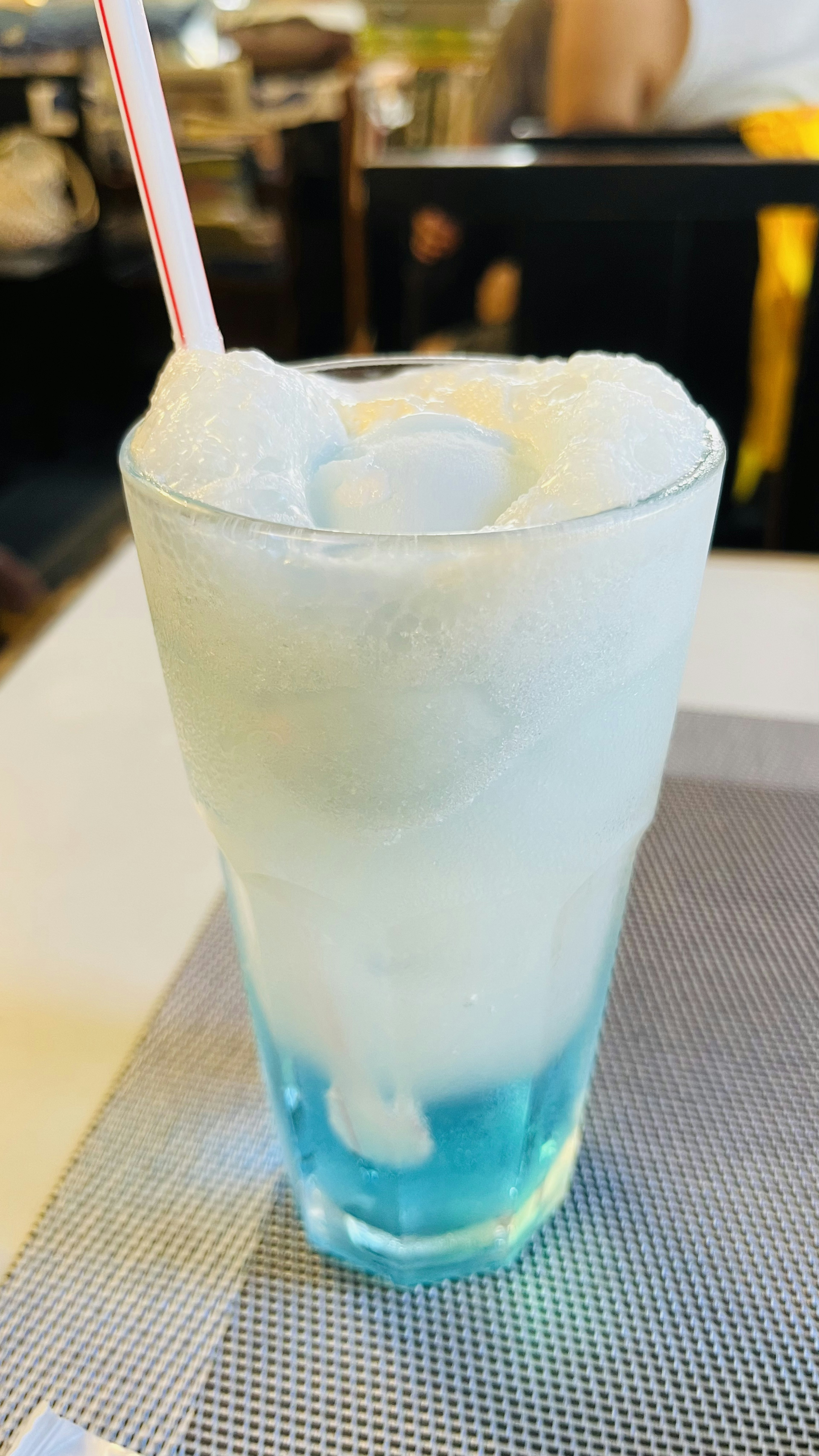 青い飲み物と白い泡のソフトクリームがトッピングされたグラス