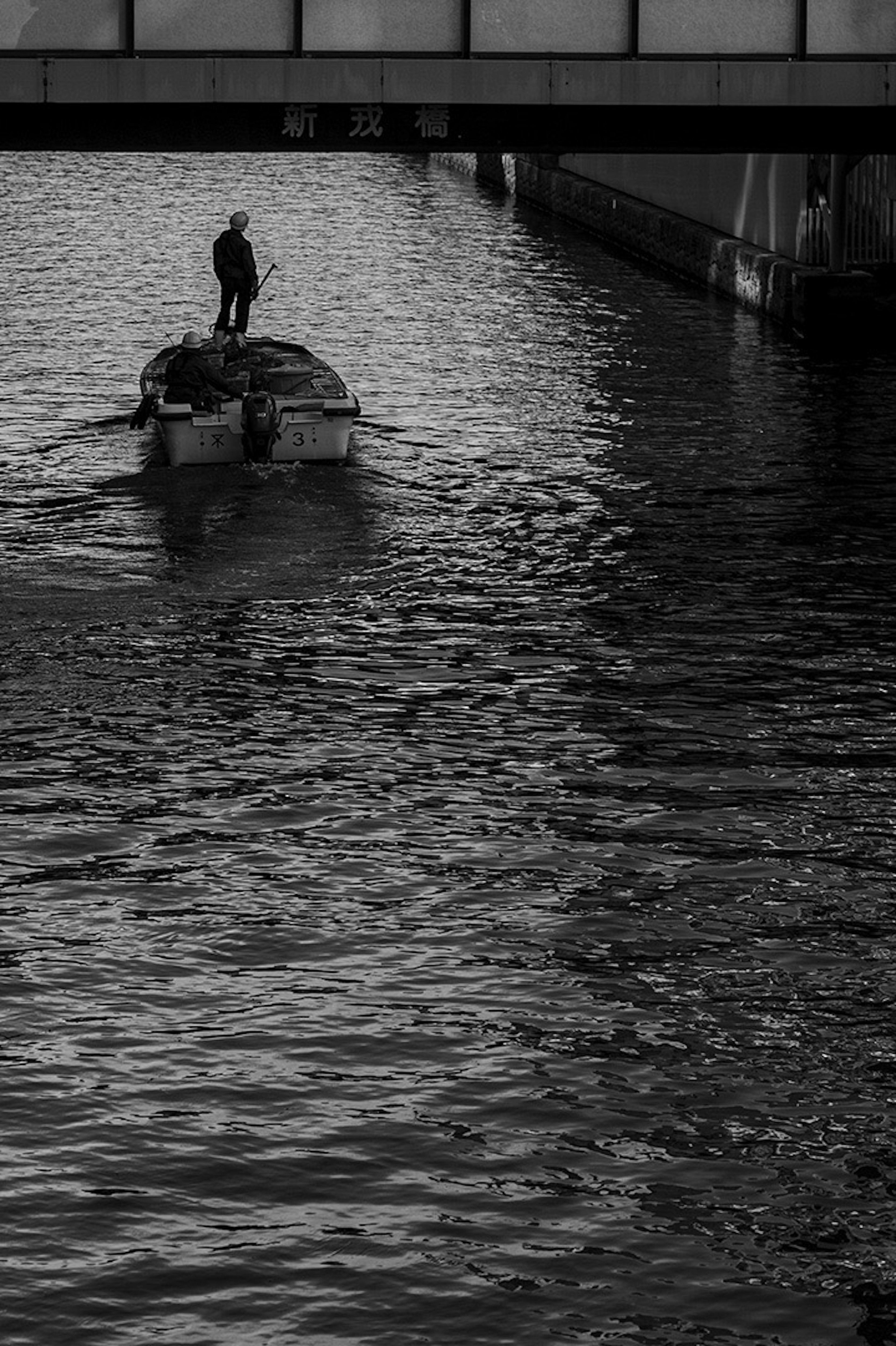 ภาพขาวดำของเรือที่เคลื่อนที่บนผิวน้ำพร้อมกับคนยืนอยู่บนเรือ