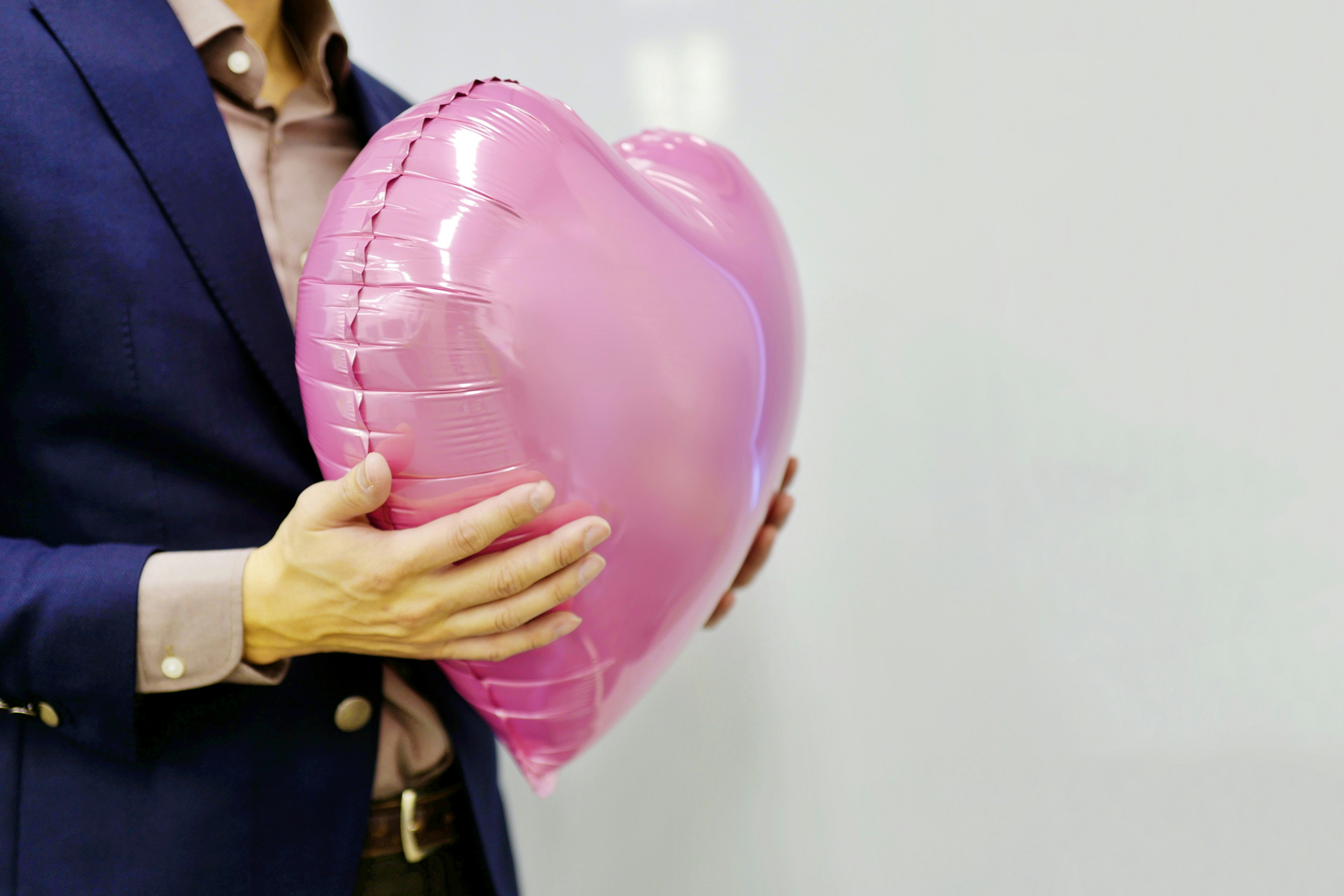 Hombre sosteniendo un globo en forma de corazón rosa