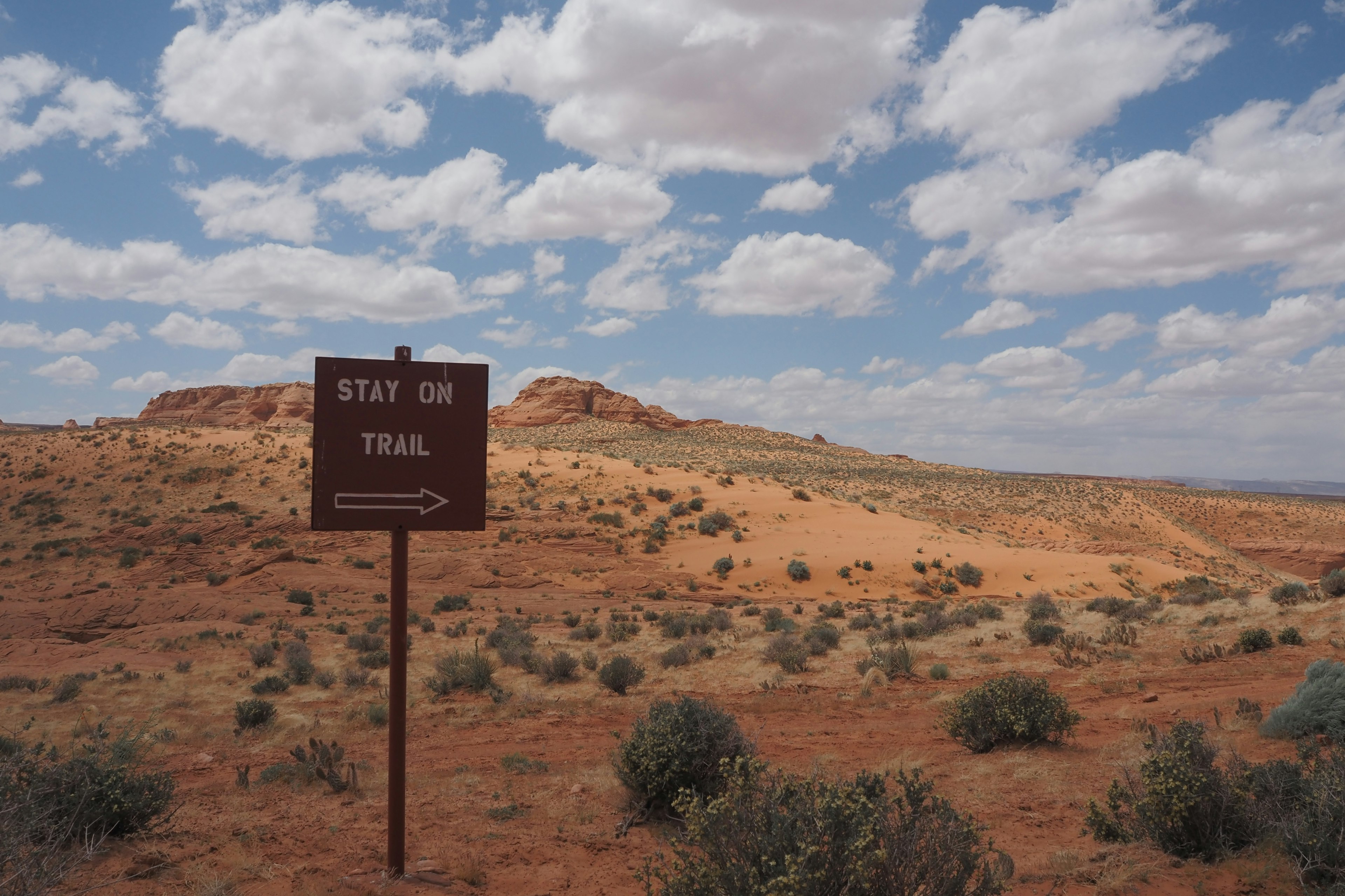 Warning sign in a red soil landscape with blue sky and clouds