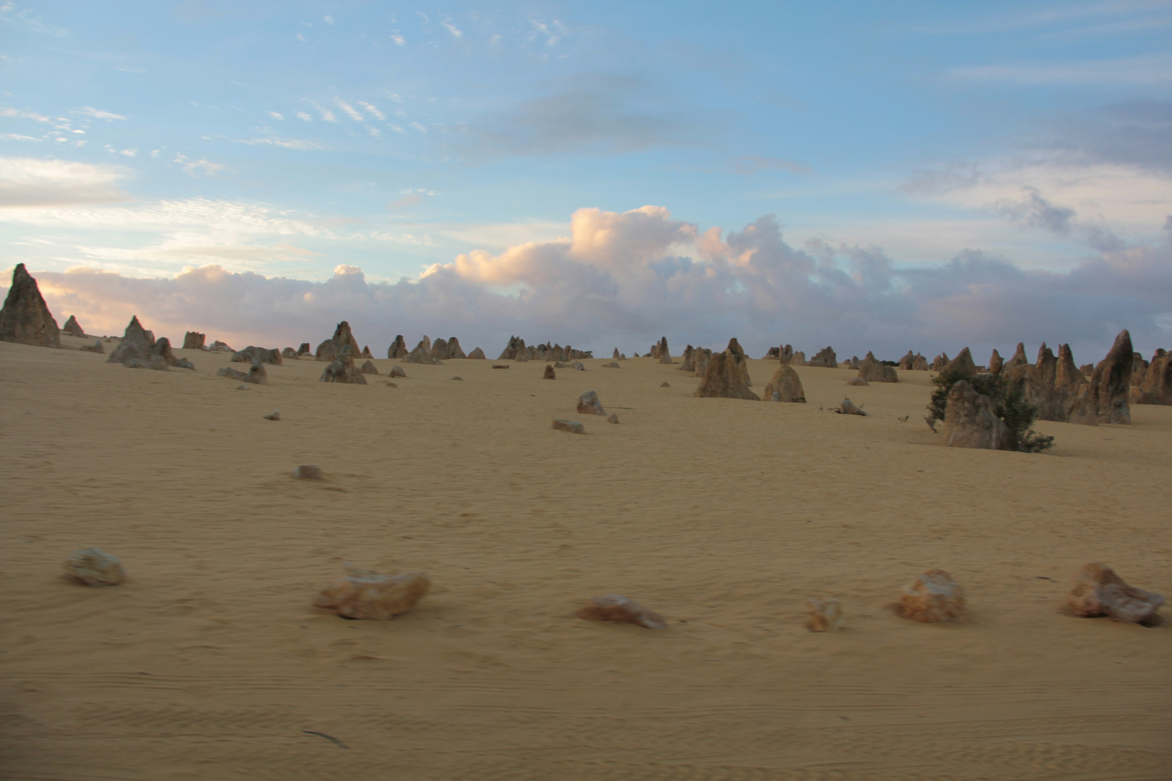 Landscape of unique rock formations in a sandy desert under a blue sky