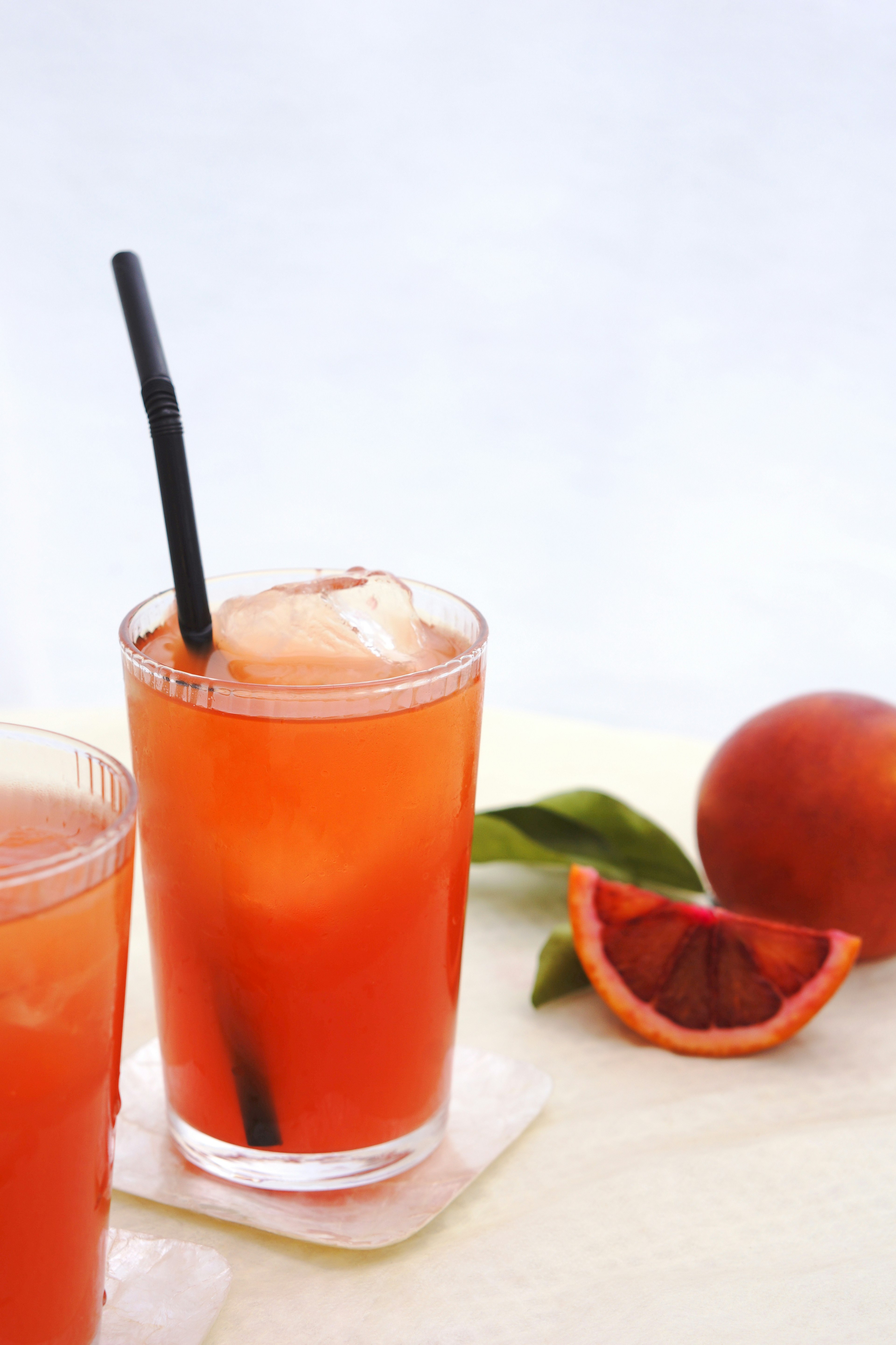 A refreshing drink with orange and blood orange served in a glass with ice