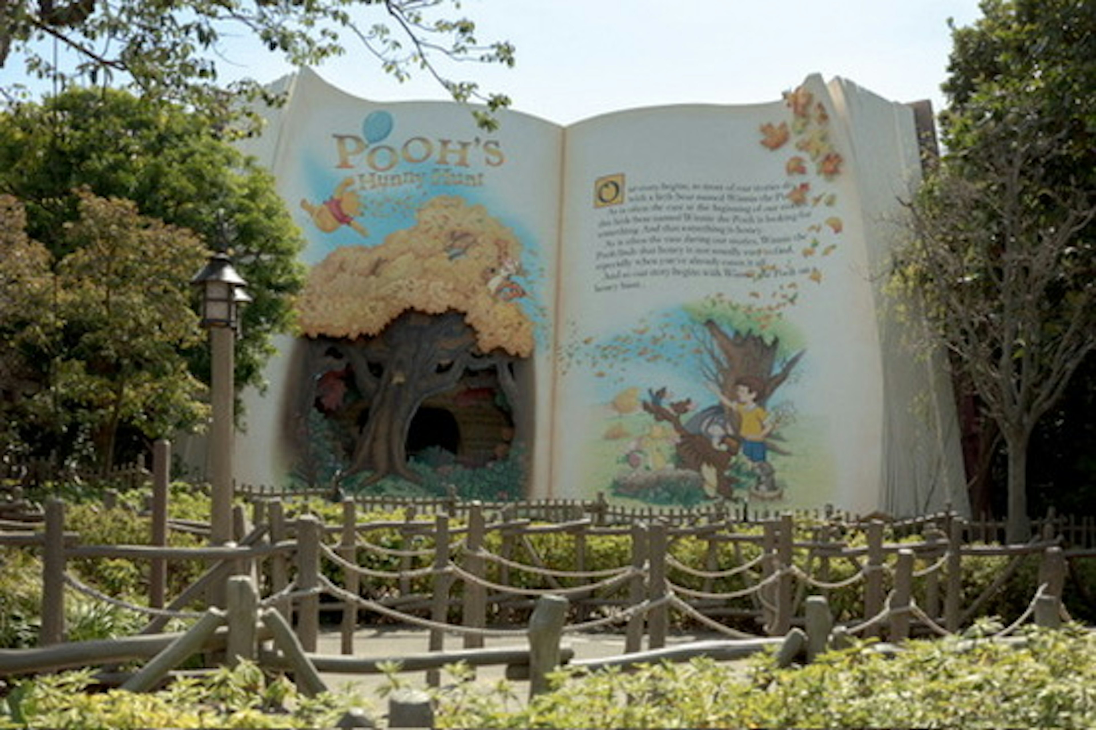 Large book-shaped artwork in a landscape with trees and flowers