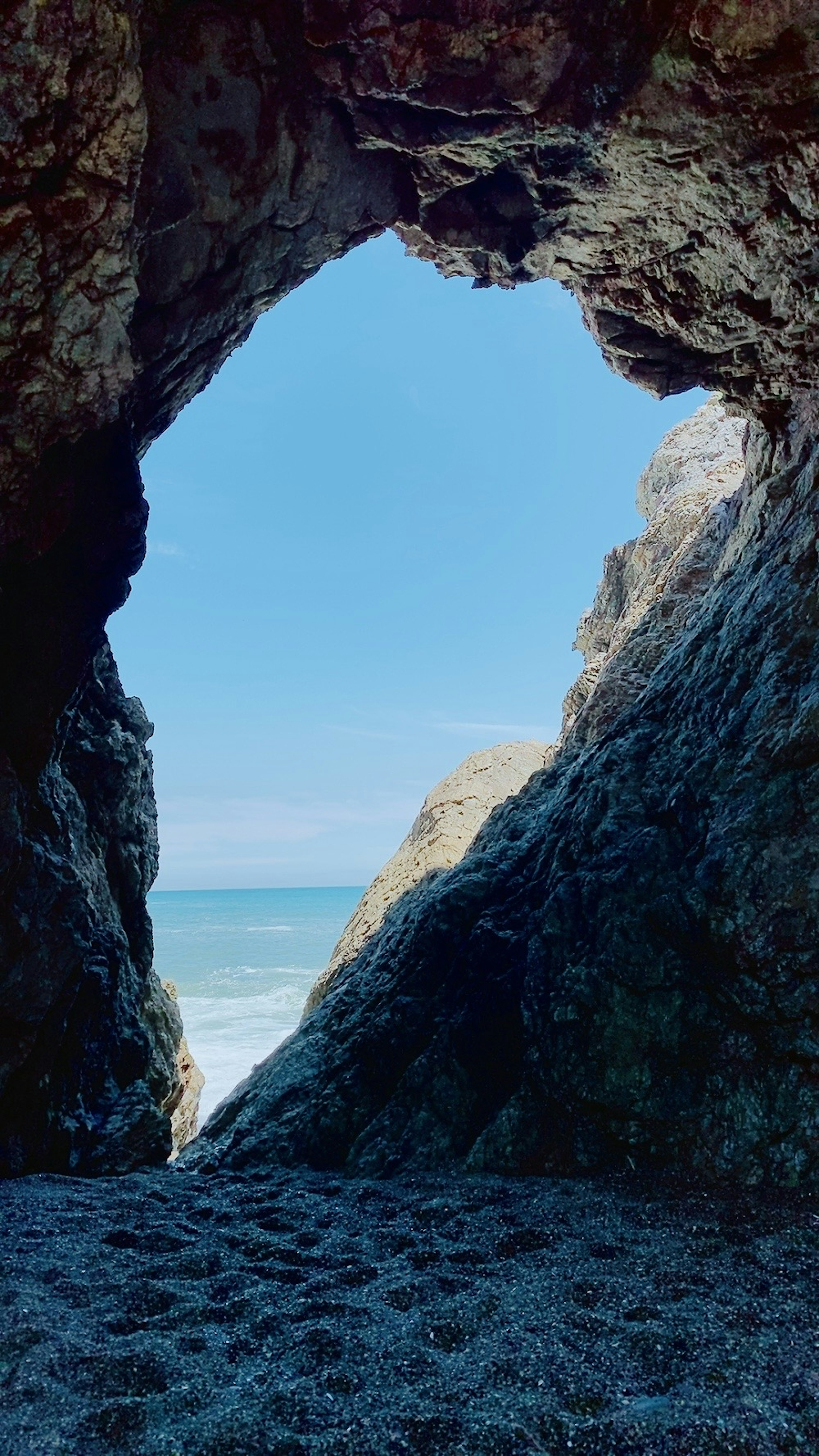 View of the sea and blue sky through a rock arch