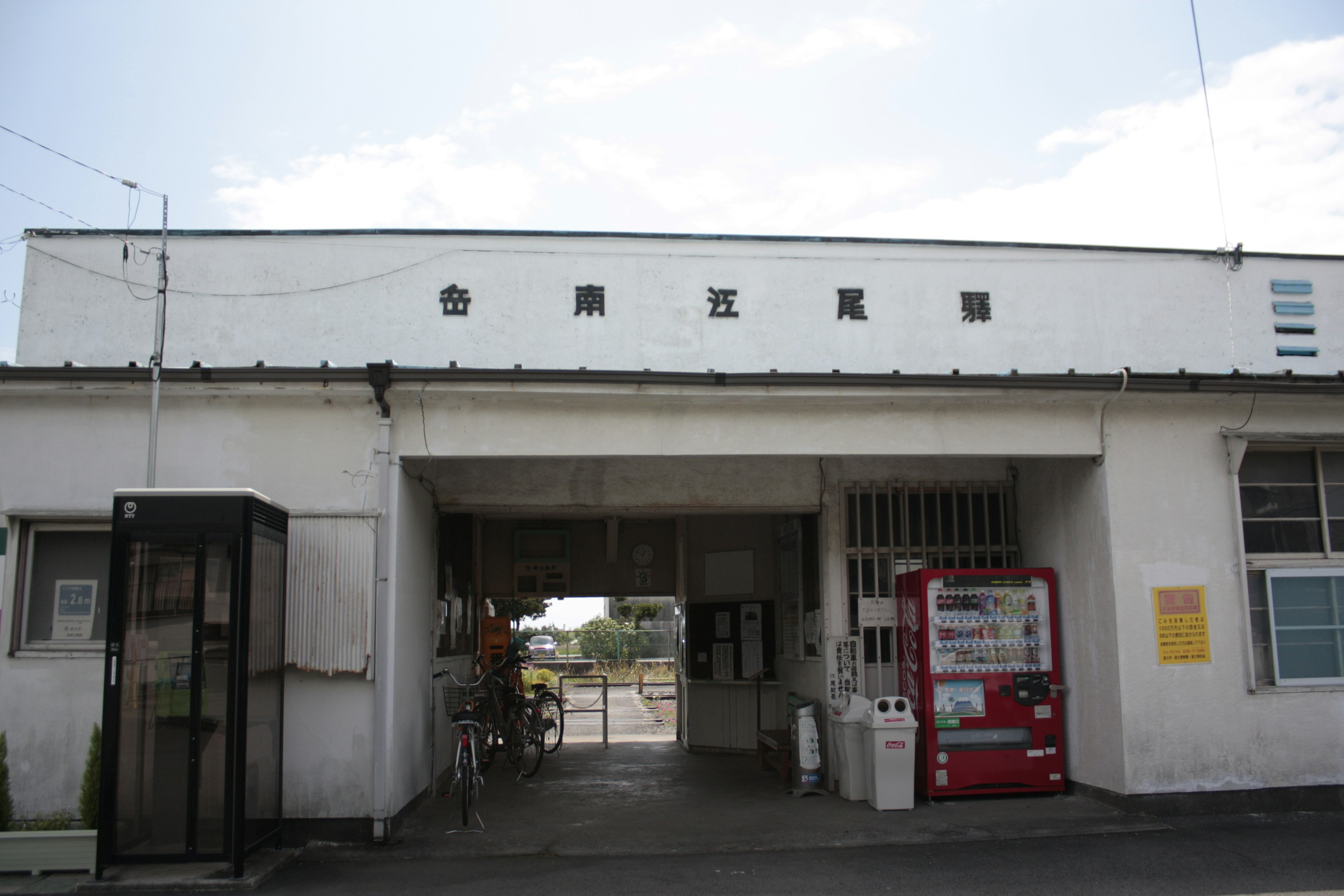 白い壁の駅舎入口と看板の写真