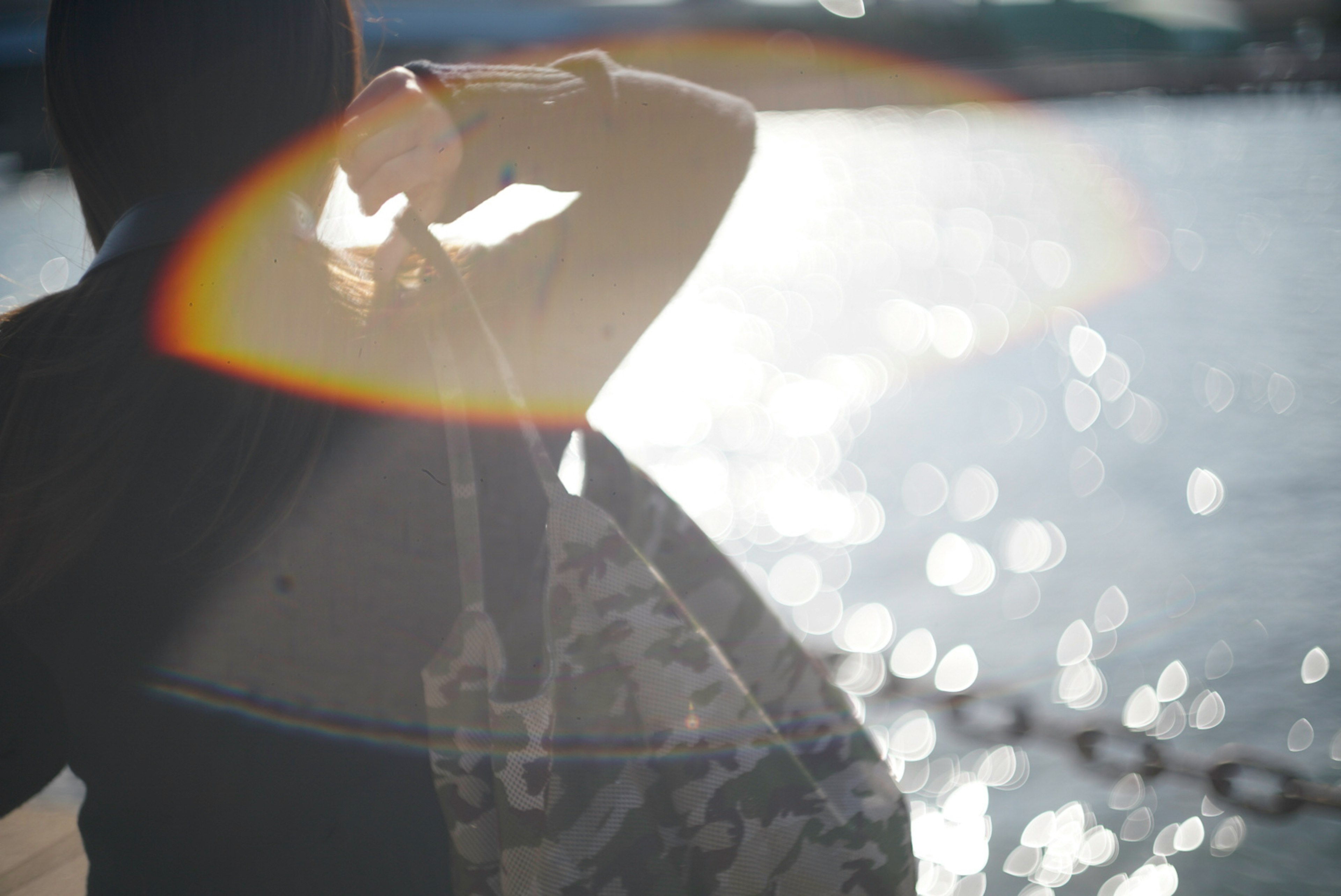 Woman viewed from behind looking at the sea Light reflection shimmering on the water surface