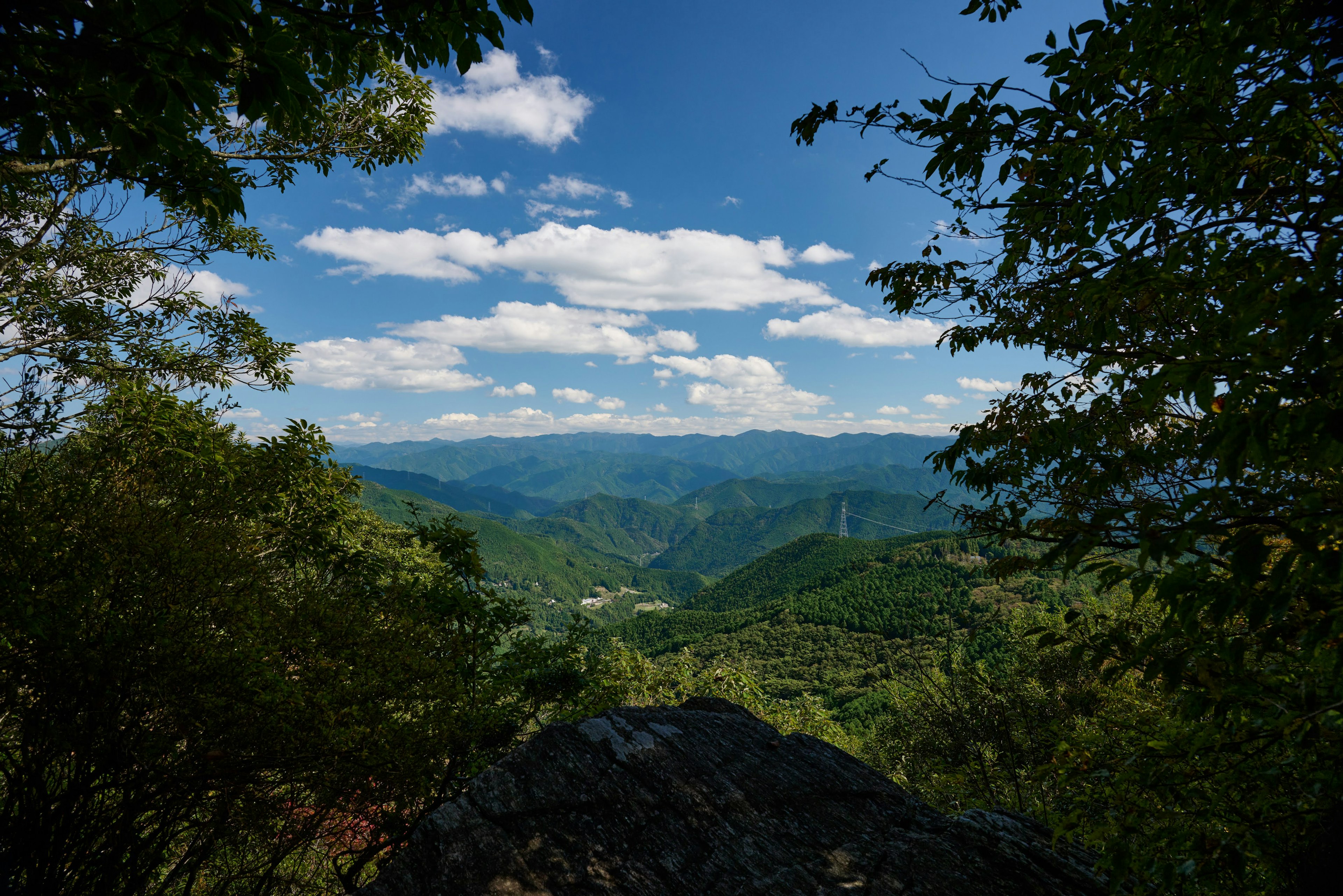 Paysage de montagne avec ciel bleu et nuages blancs entouré d'arbres verts luxuriants