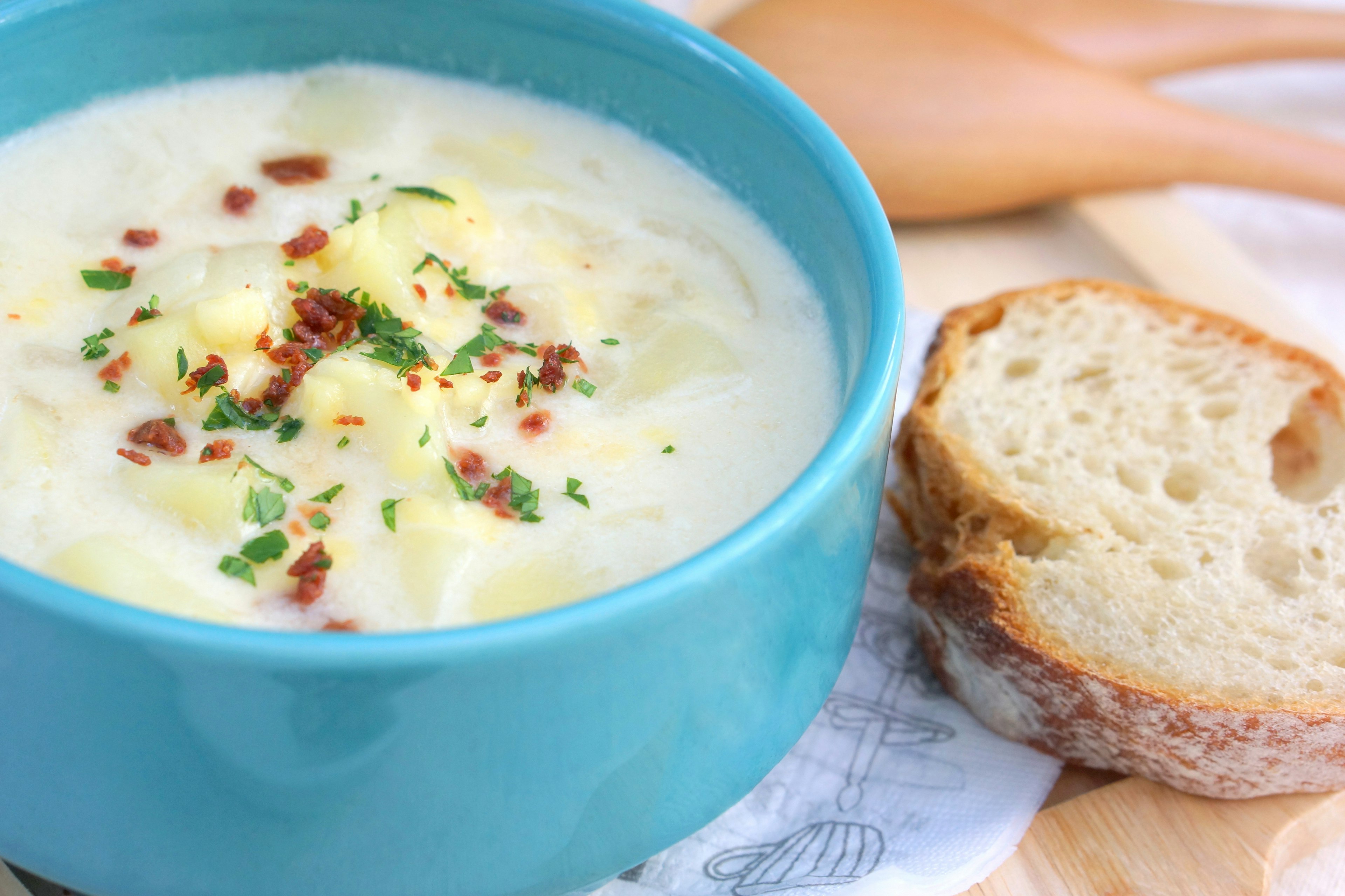 Cremige Suppe in einer türkisfarbenen Schüssel mit Brot daneben