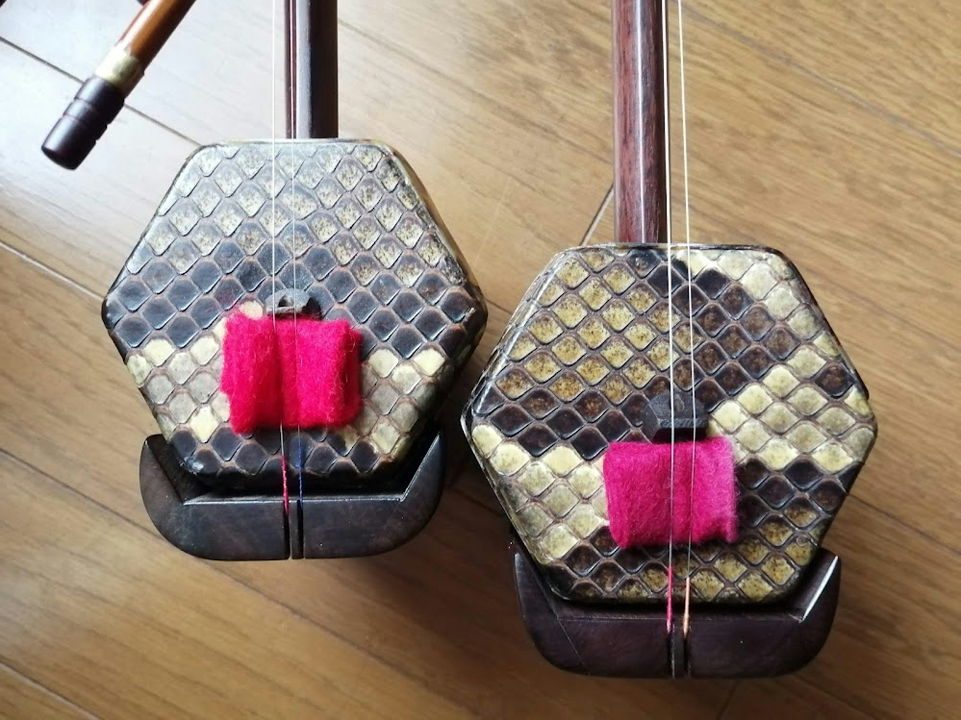 Imagen de dos instrumentos tradicionales con cuerpos hexagonales y decoraciones rosas vibrantes