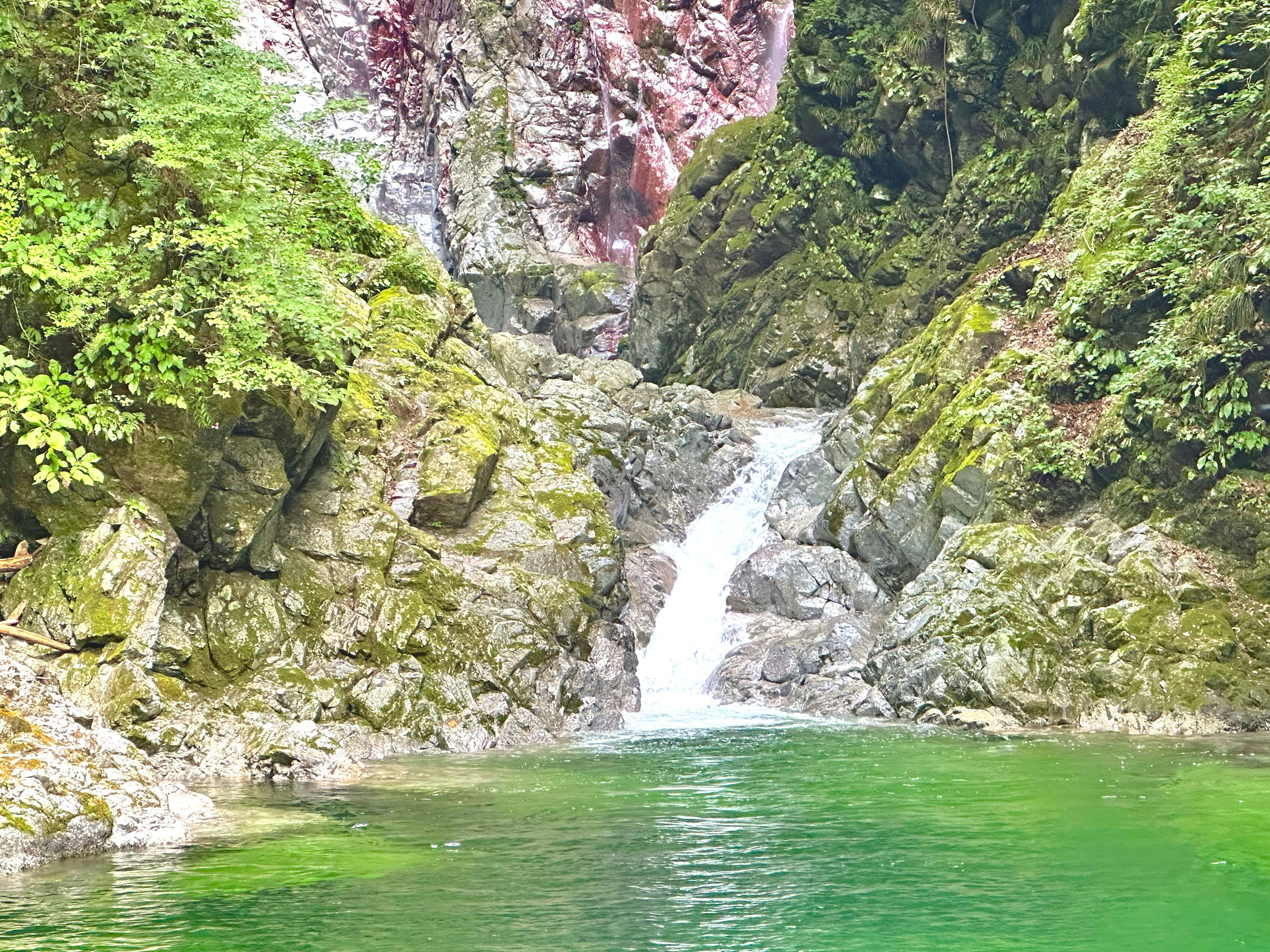 Hermosa cascada rodeada de rocas y vegetación exuberante con agua esmeralda