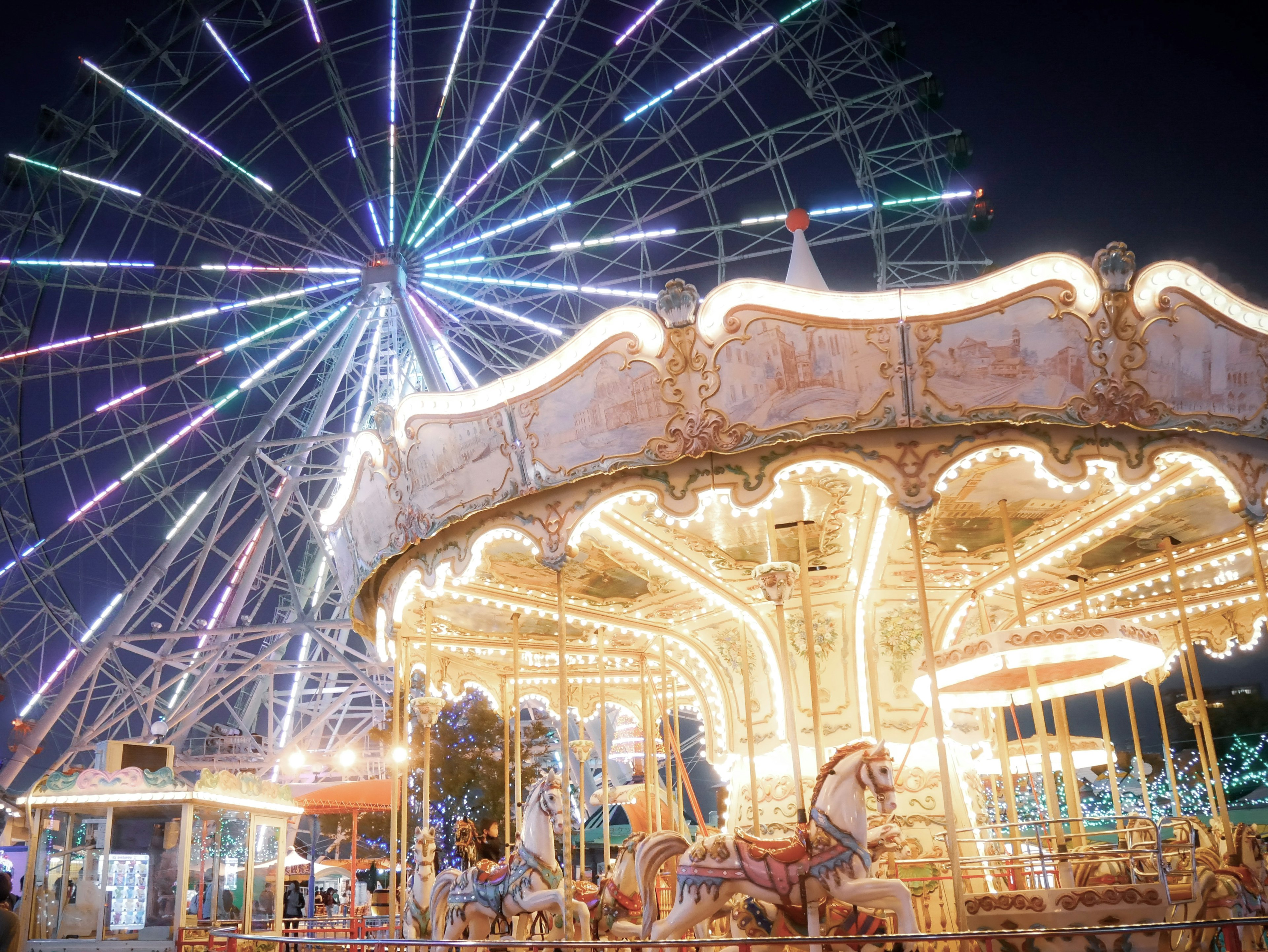 Ferris wheel and carousel illuminated at night in an amusement park