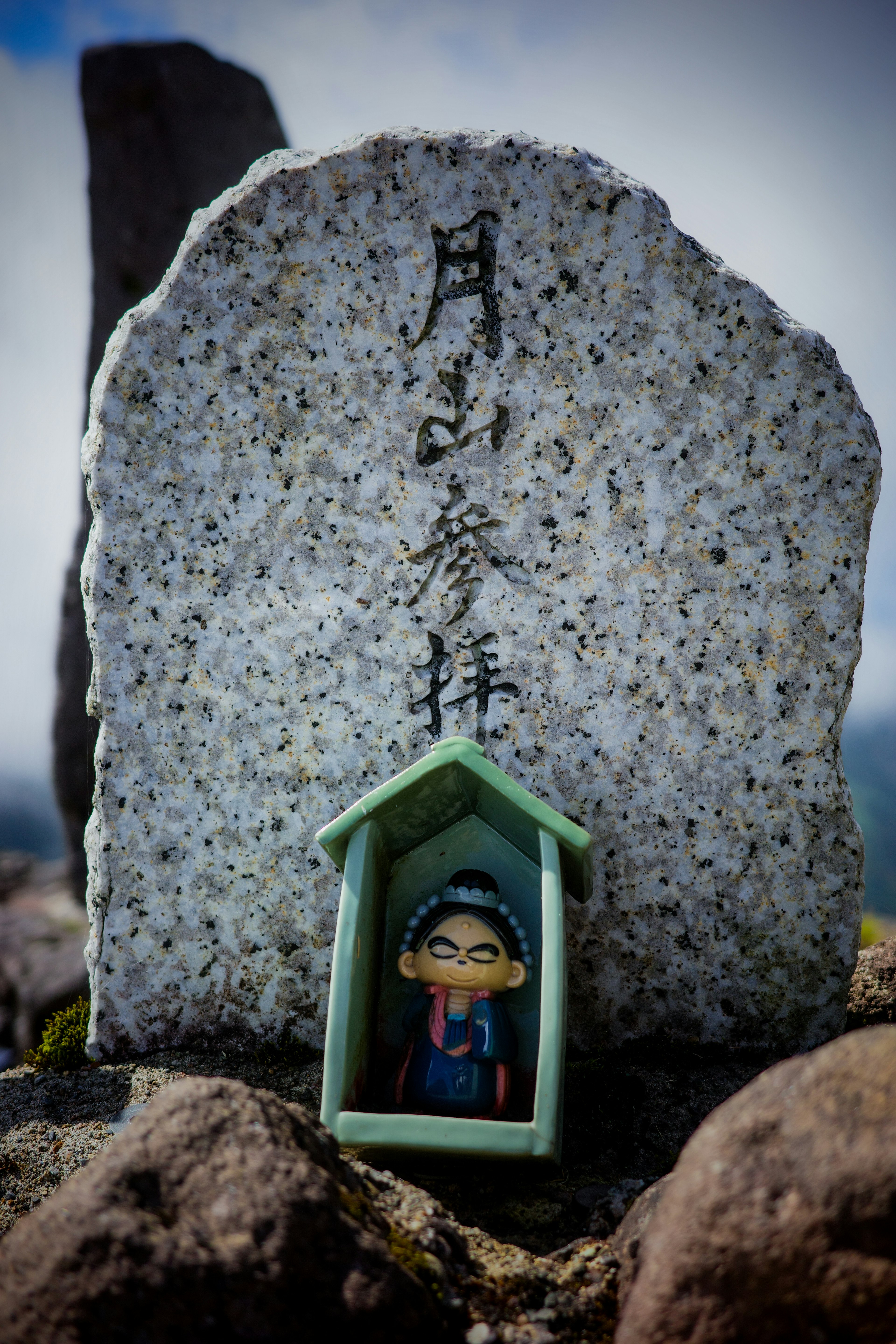 Une petite figurine devant un monument en pierre avec des inscriptions