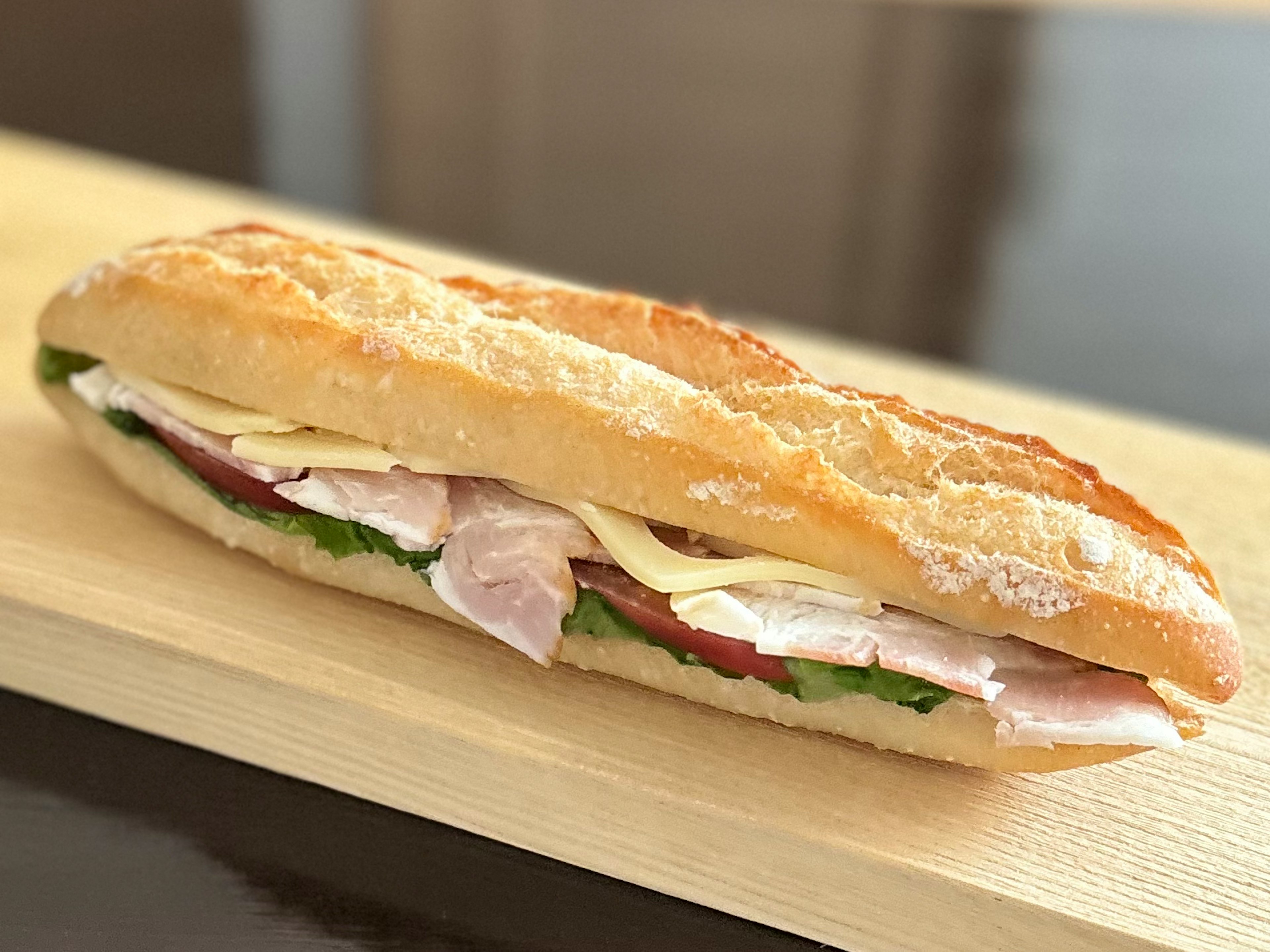 Un delizioso panino preparato con una baguette farcita di prosciutto e formaggio