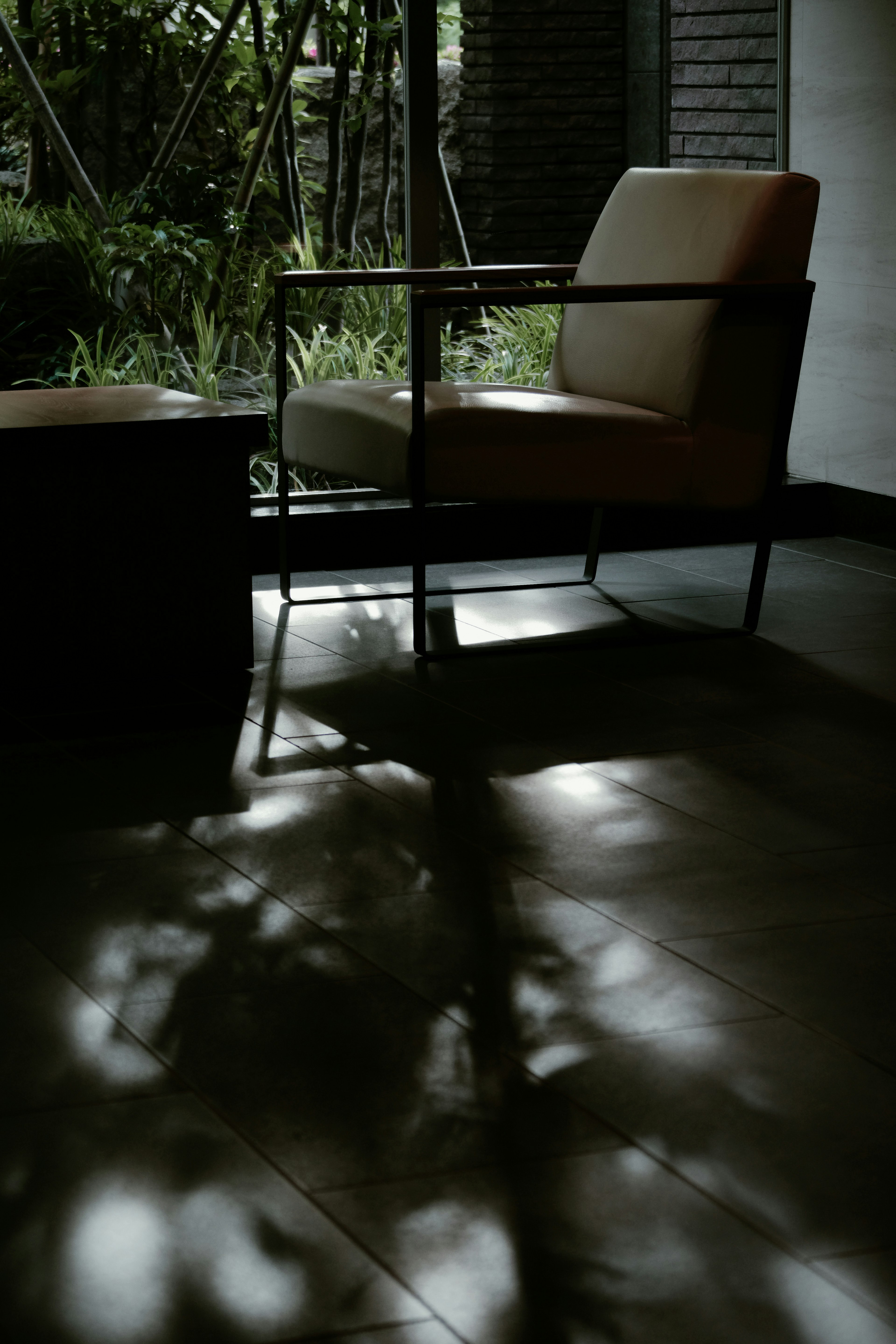 A quiet indoor scene featuring a chair and table casting shadows